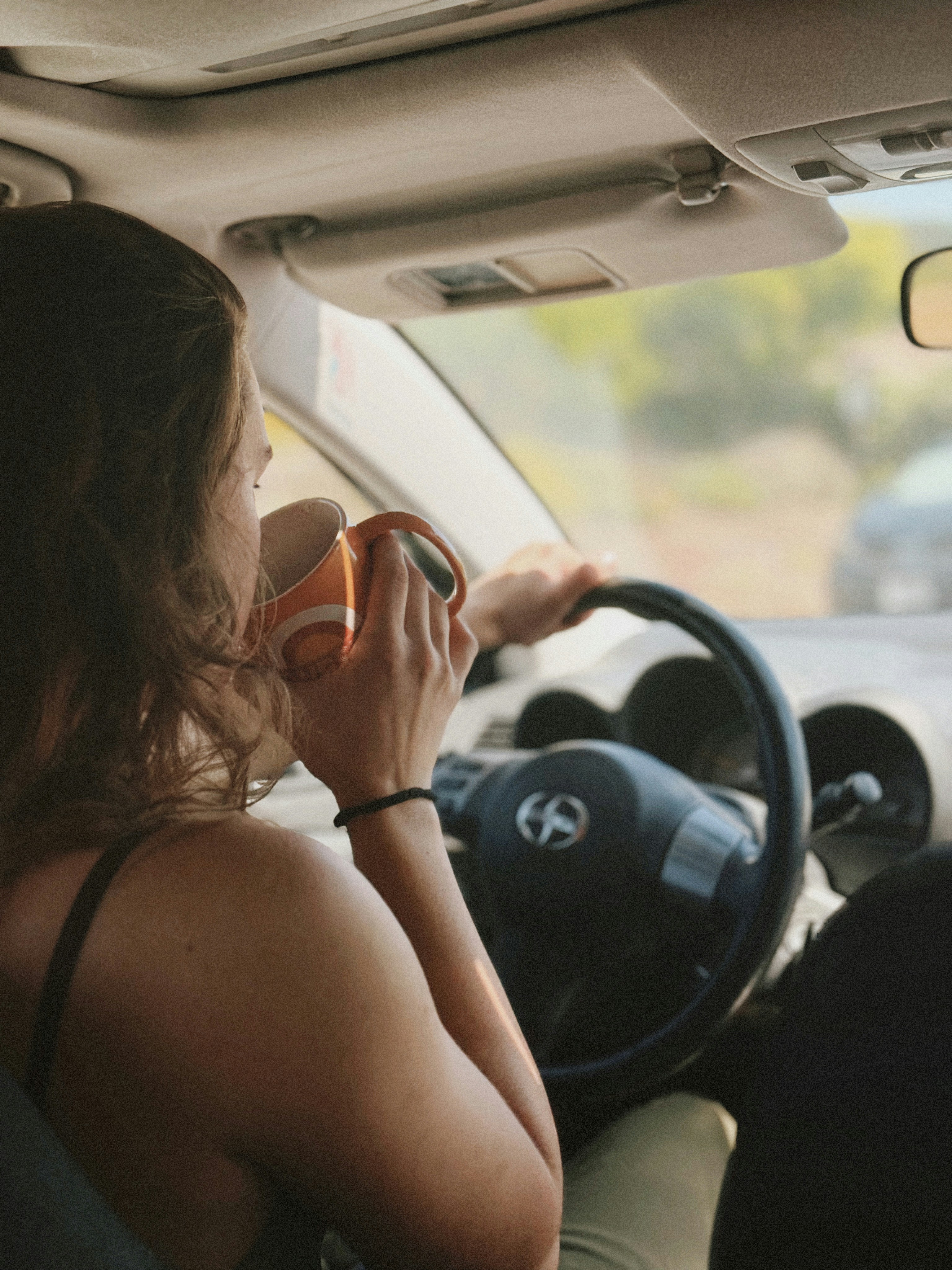 Mujer tomando café mientras conduce un automóvil