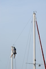 Sailors working on a tall sailboat mast