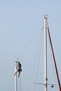 Sailors working on a tall sailboat mast