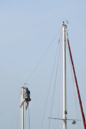 Sailors working on a tall sailboat mast