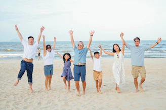A happy family with arms raised on the beach.