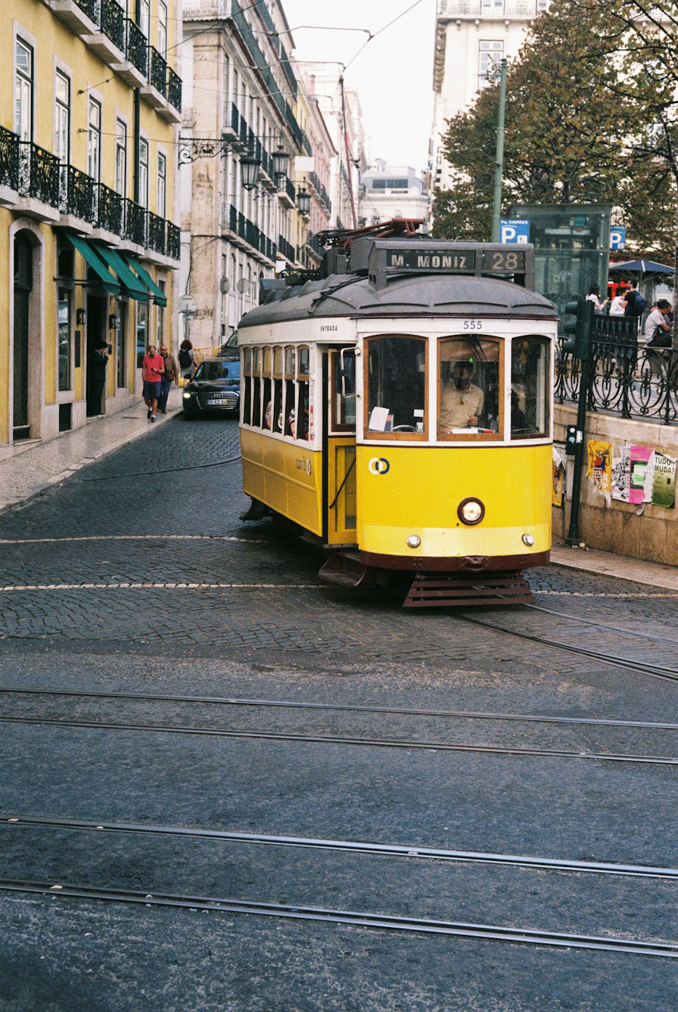 A yellow tram on Lisbon's cobbles on a summer morning