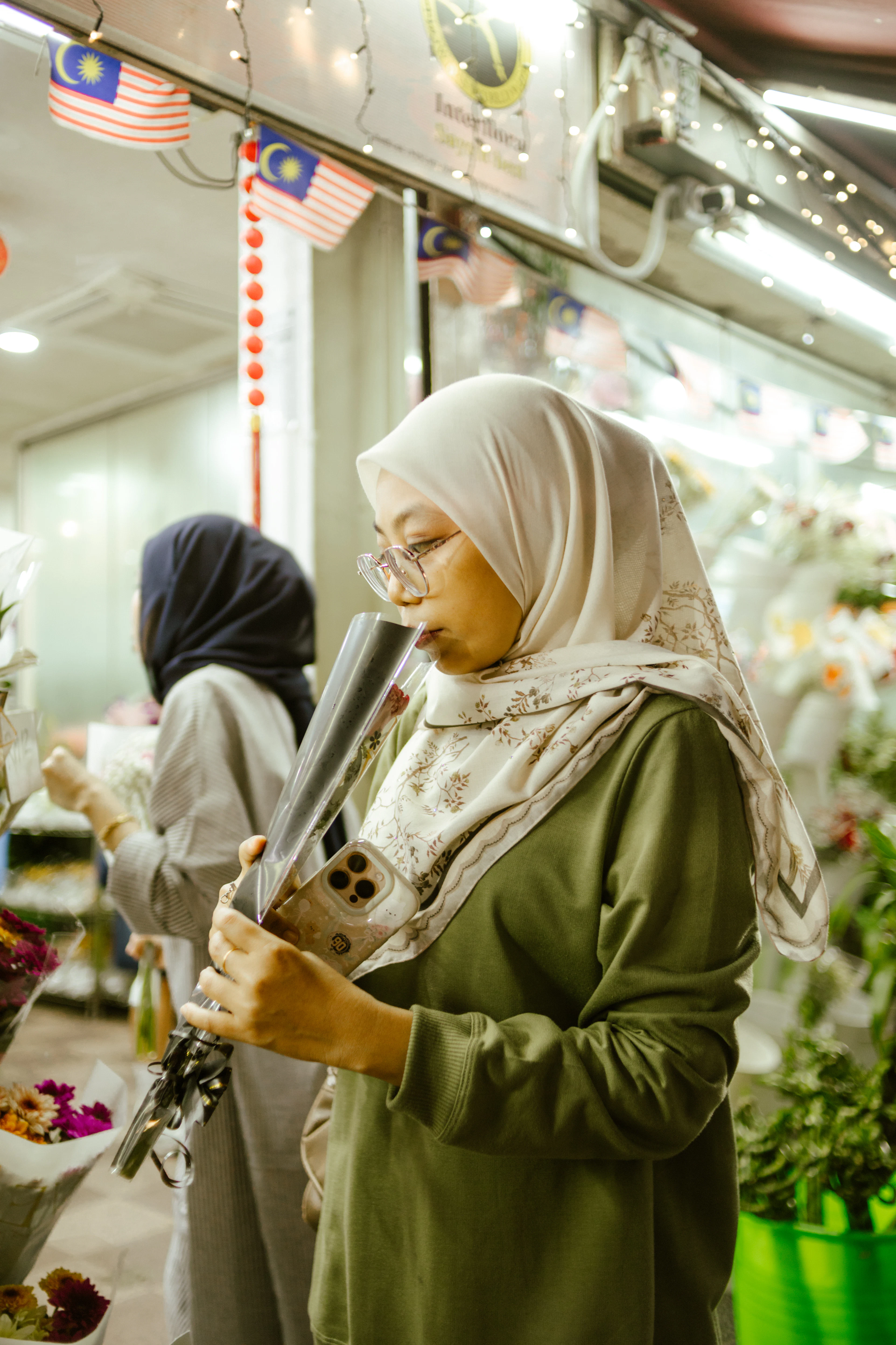 Wanita bertudung memeriksa telefon di kedai bunga