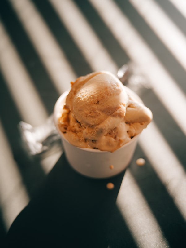 A single creamy scoop of cinnamon oatmeal cookie ice cream in a white cup showing smooth, dense custard texture