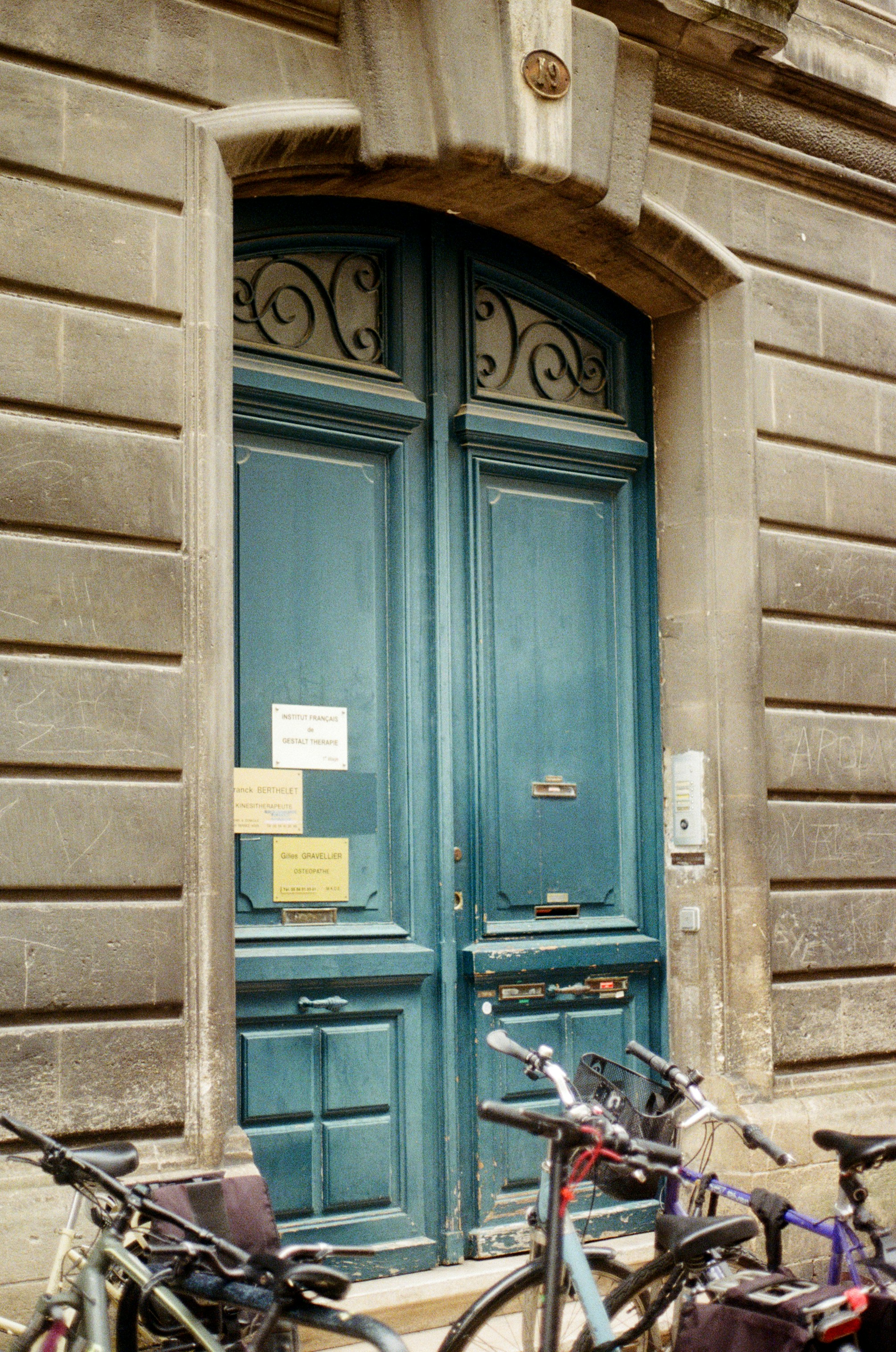 Old teal double doors with bicycles parked outside