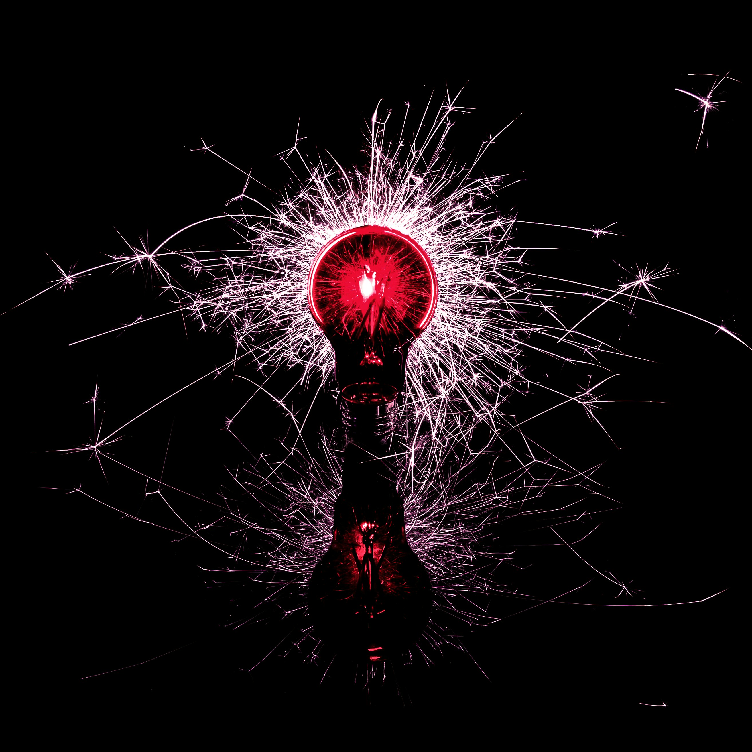 Red light bulb with sparks on a dark background