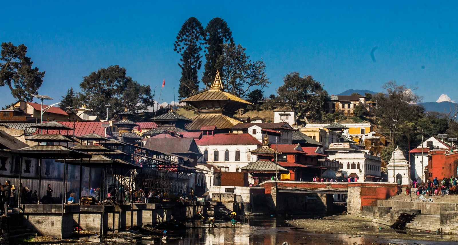 The gilded roof of Pashupatinath above stone ghats and shrines on the Bagmati river in Kathmandu