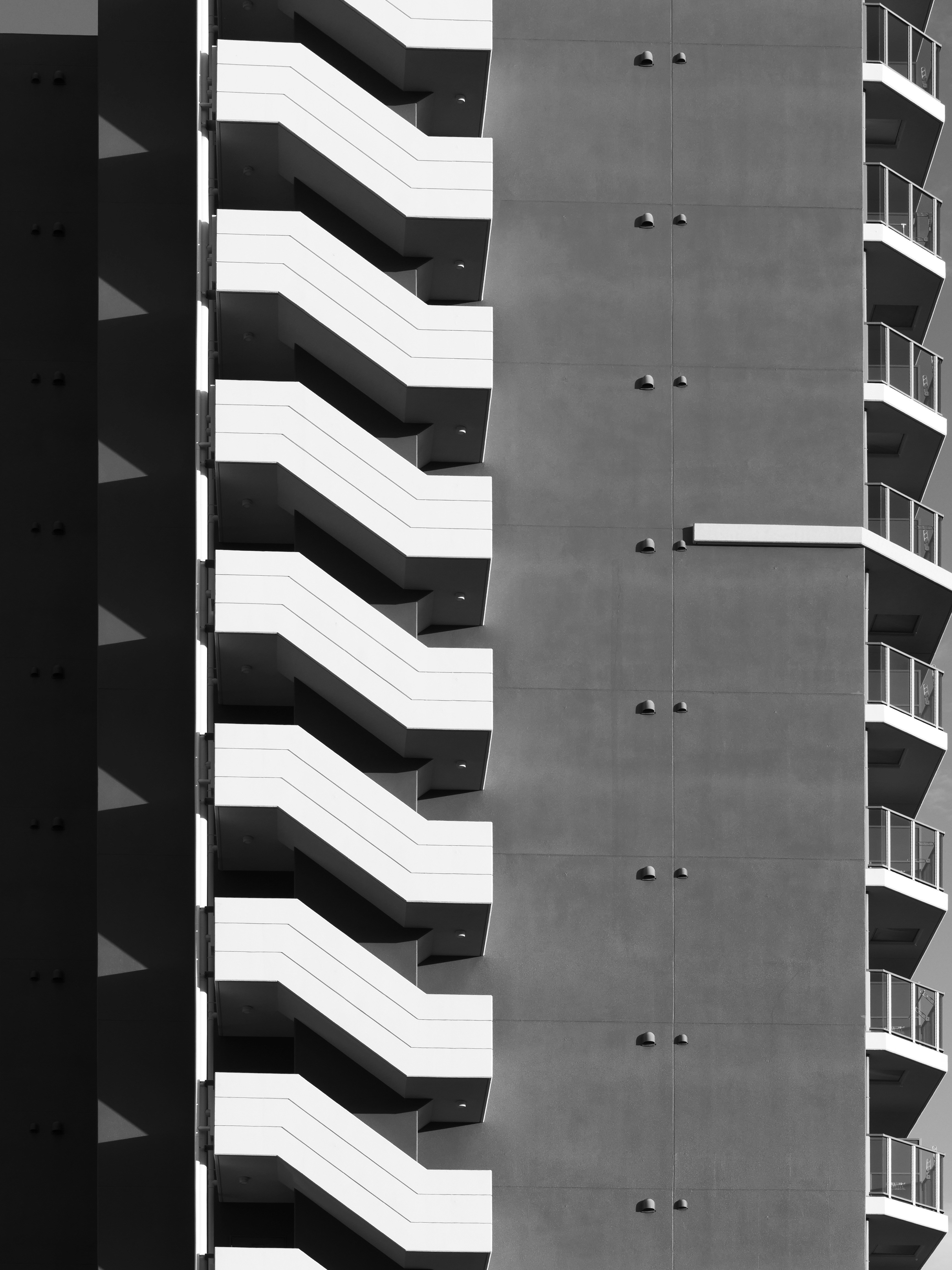 Modern building with repeating white staircases and balconies.