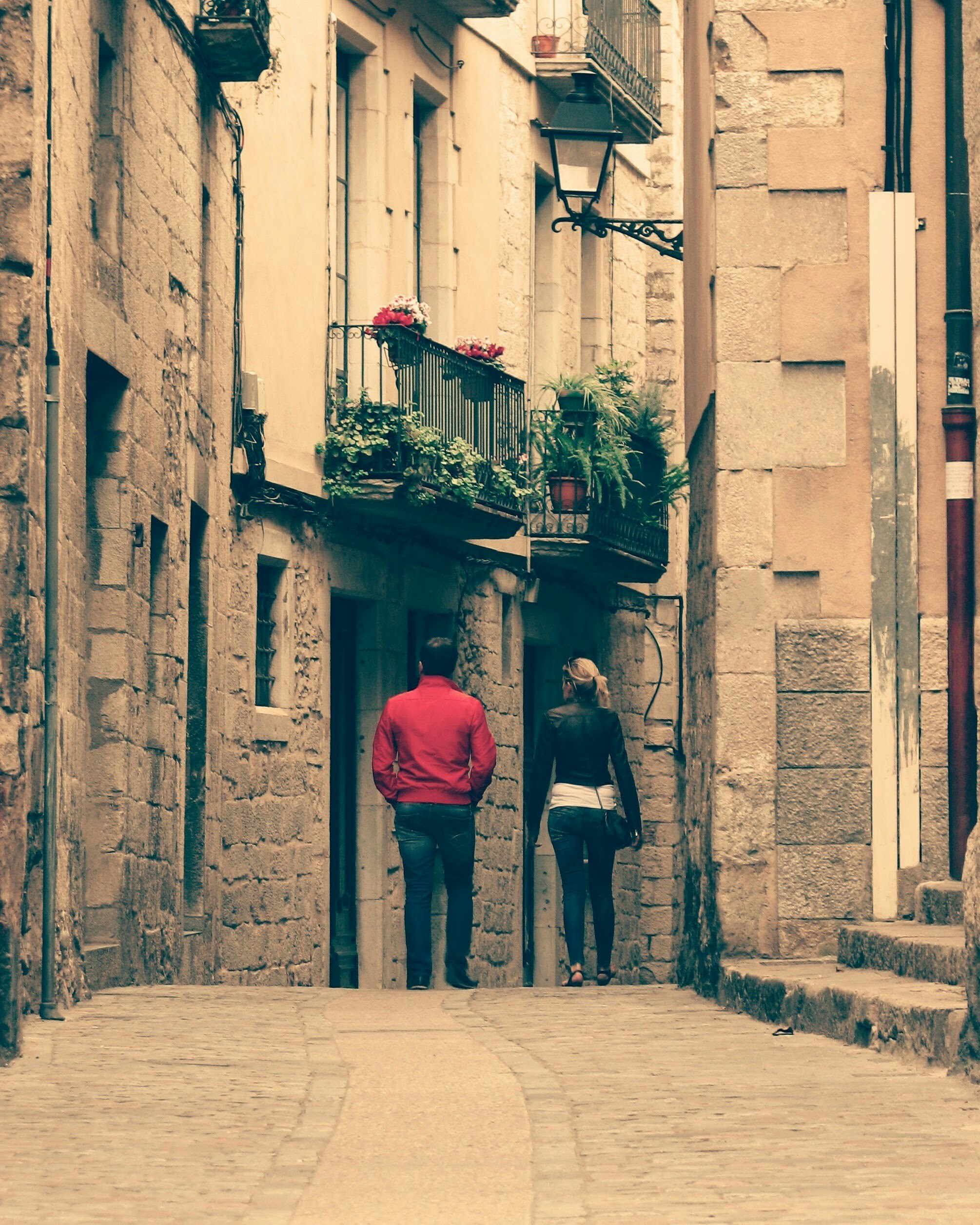 Two people stand at the end of a narrow street.