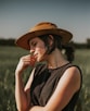 Woman in hat with hand on chin in field