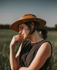 Woman in hat with hand on chin in field