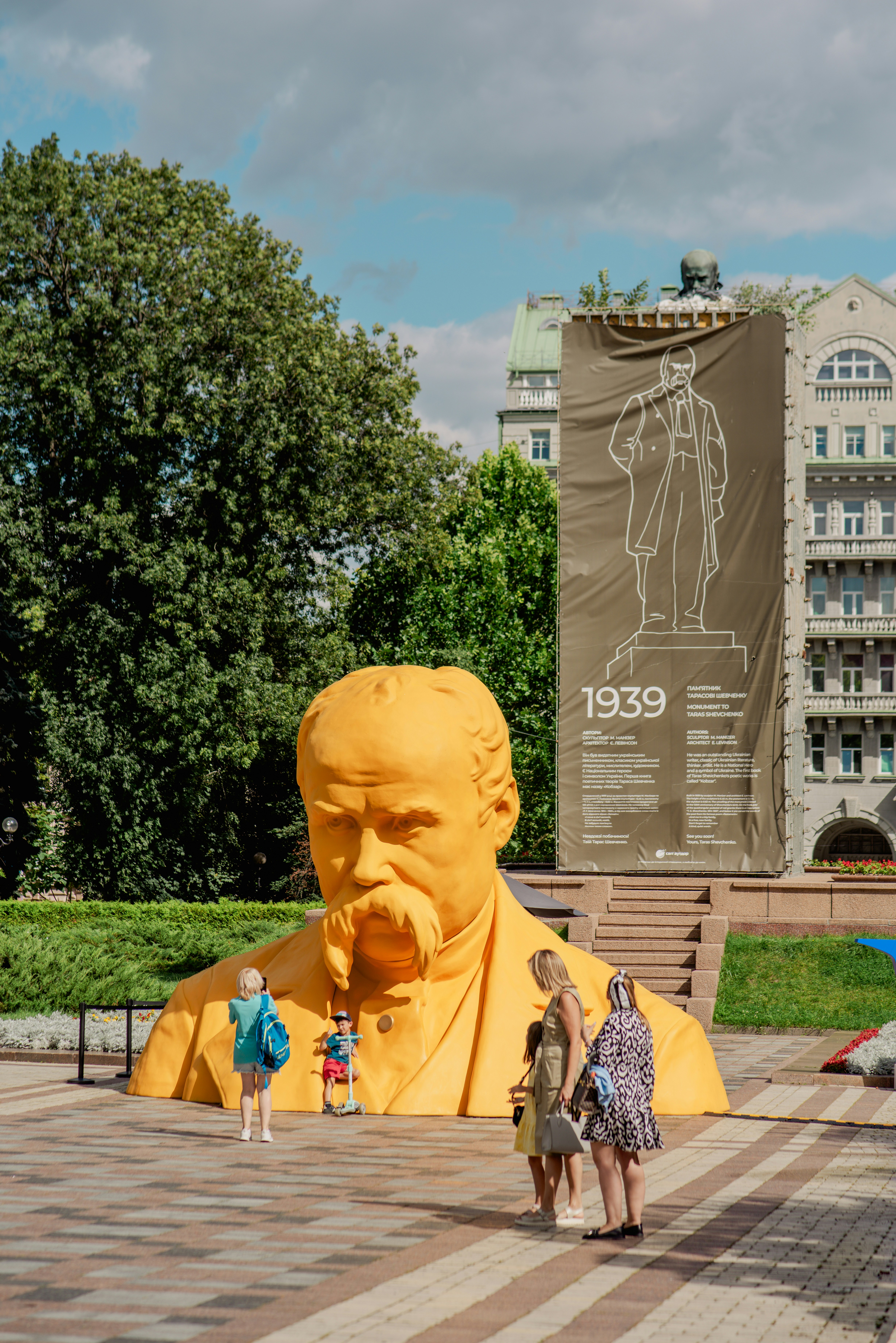 Giant yellow sculpture of a man's head and shoulders.