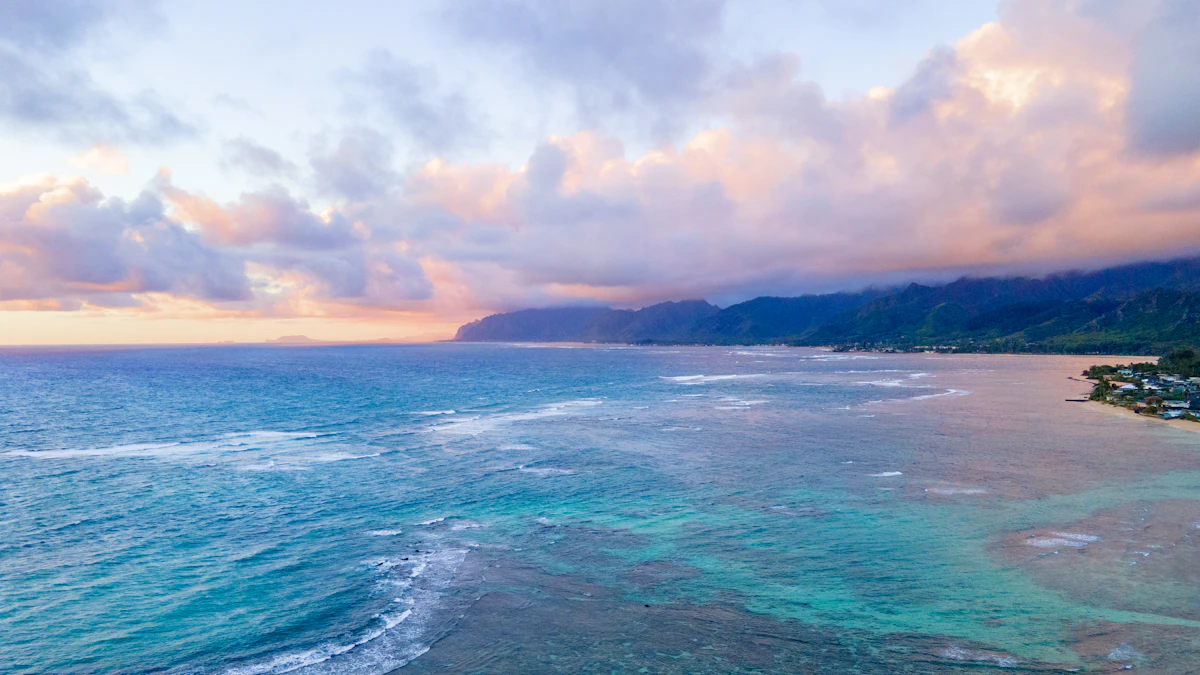 Calm turquoise ocean waves meeting a tropical coastline at sunset