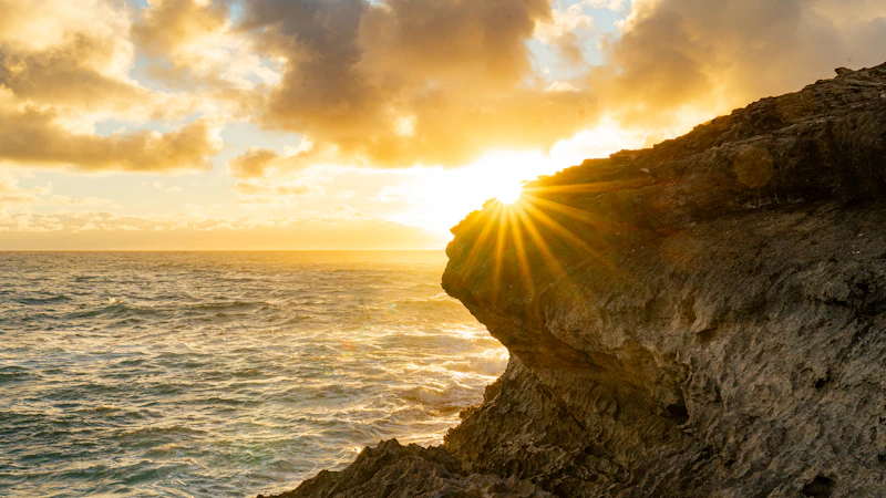 Sun setting over an ocean cliff