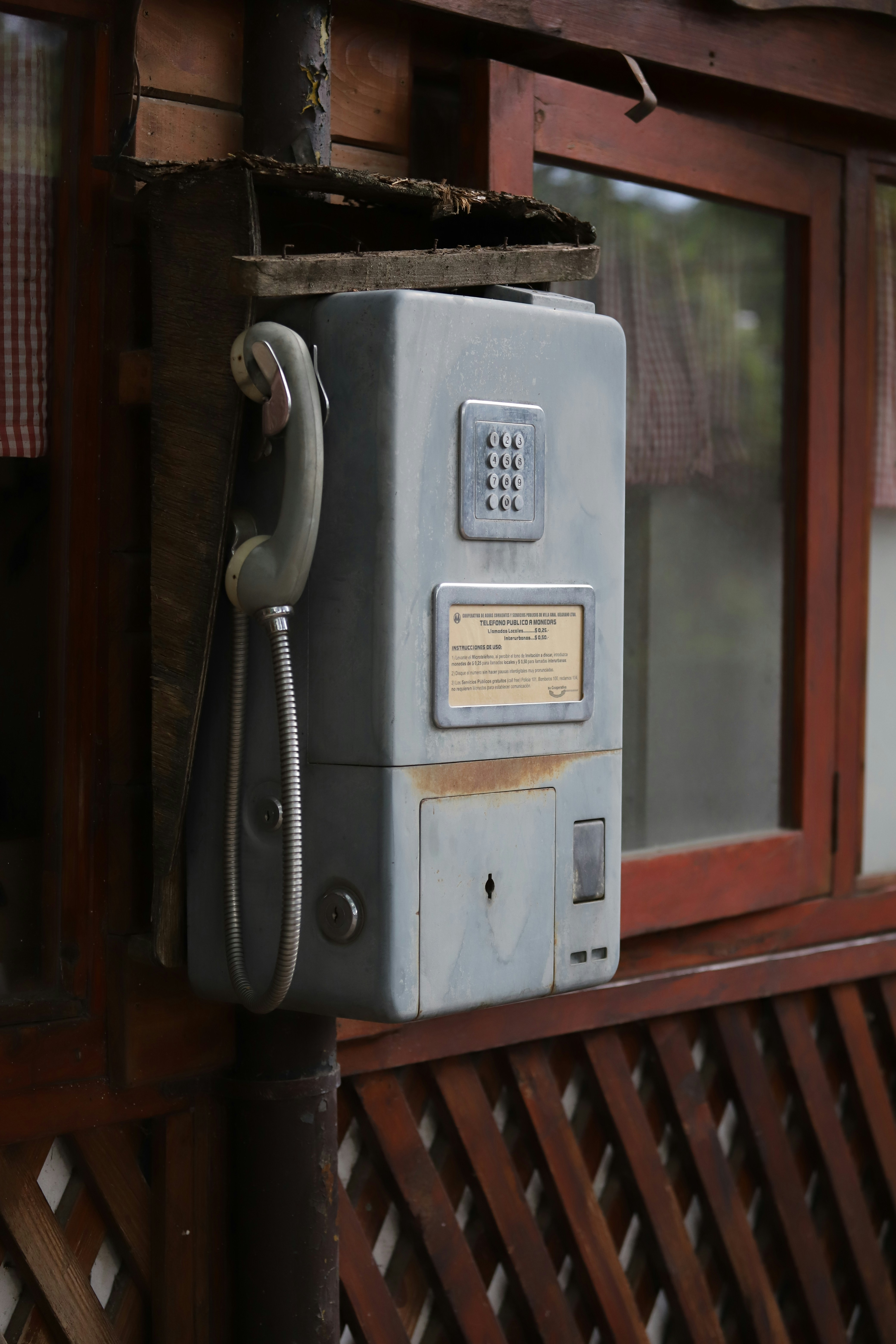 An old payphone mounted on a wooden wall.