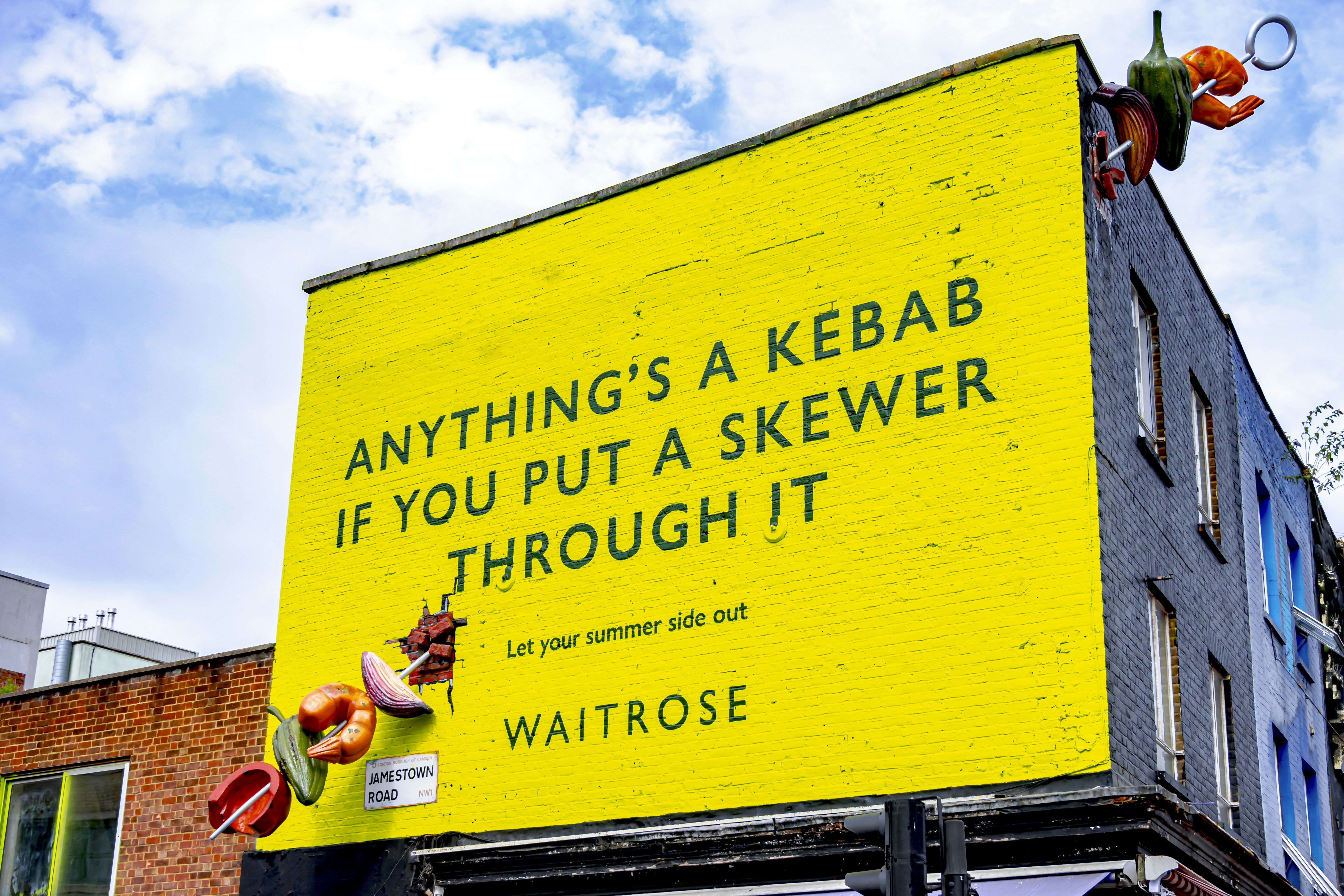 Yellow billboard with text about kebabs and skewers.