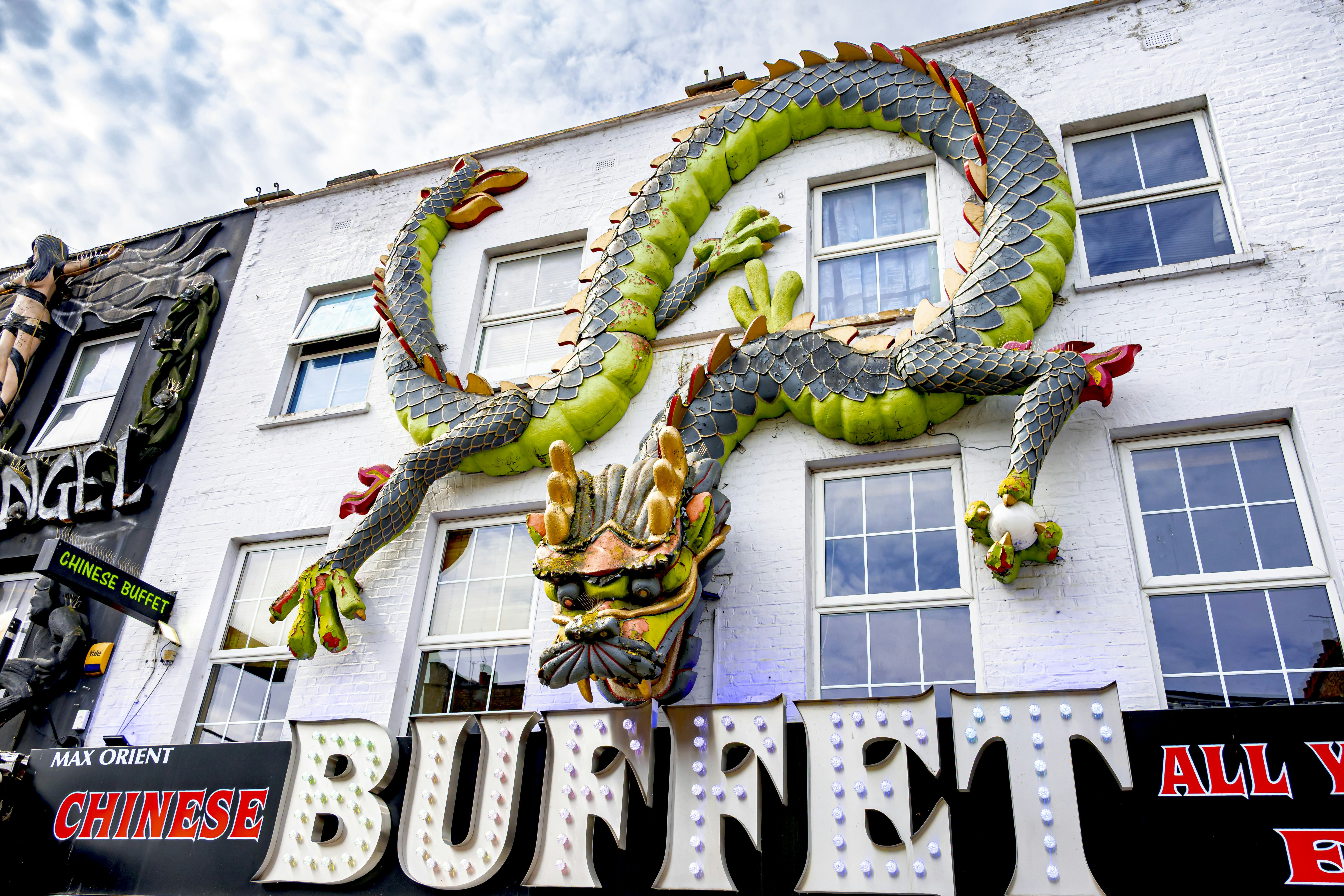 Dragon sculpture on a building above a buffet sign.