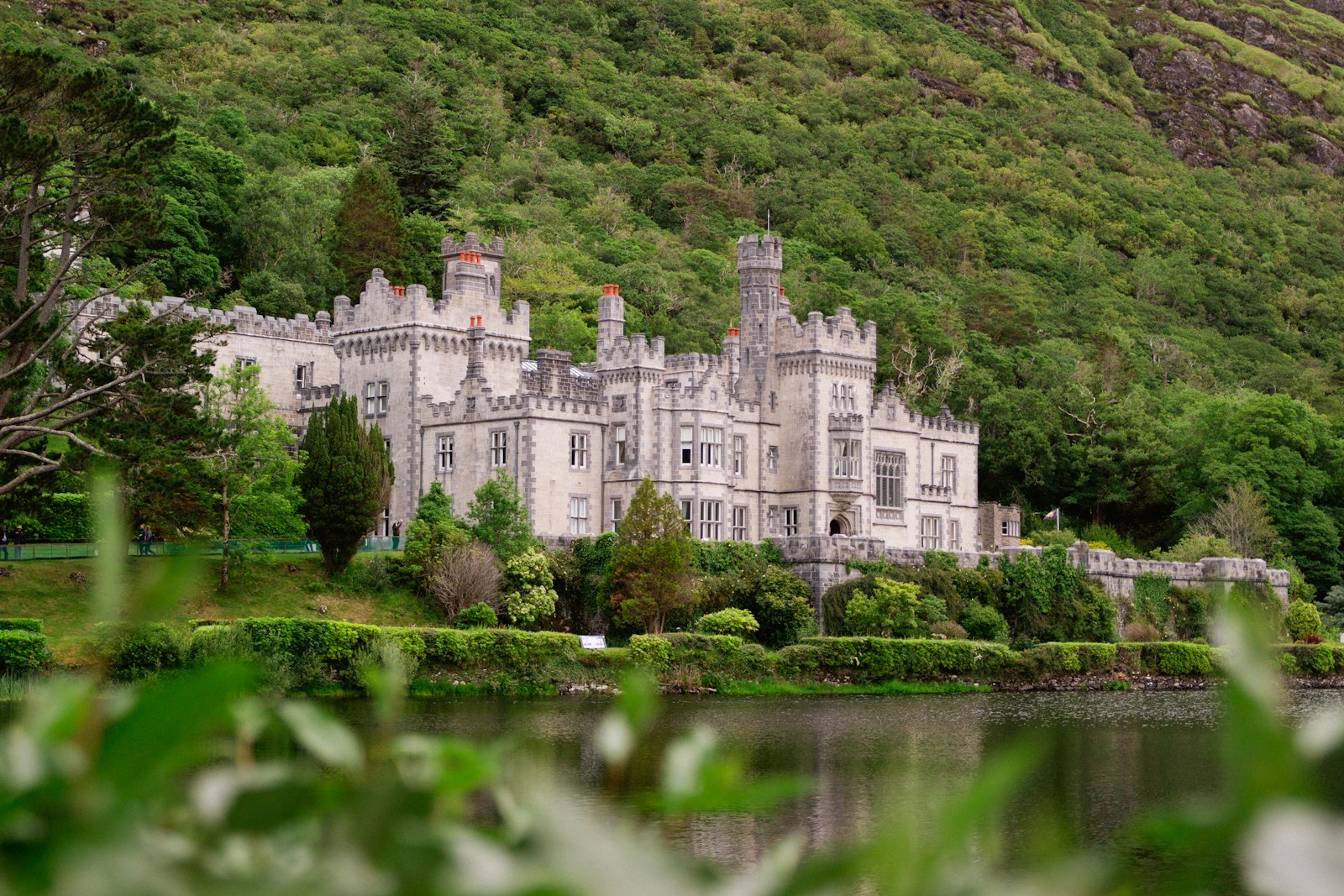 Kylemore Abbey's white facade among green woodland beside a lake in Connemara