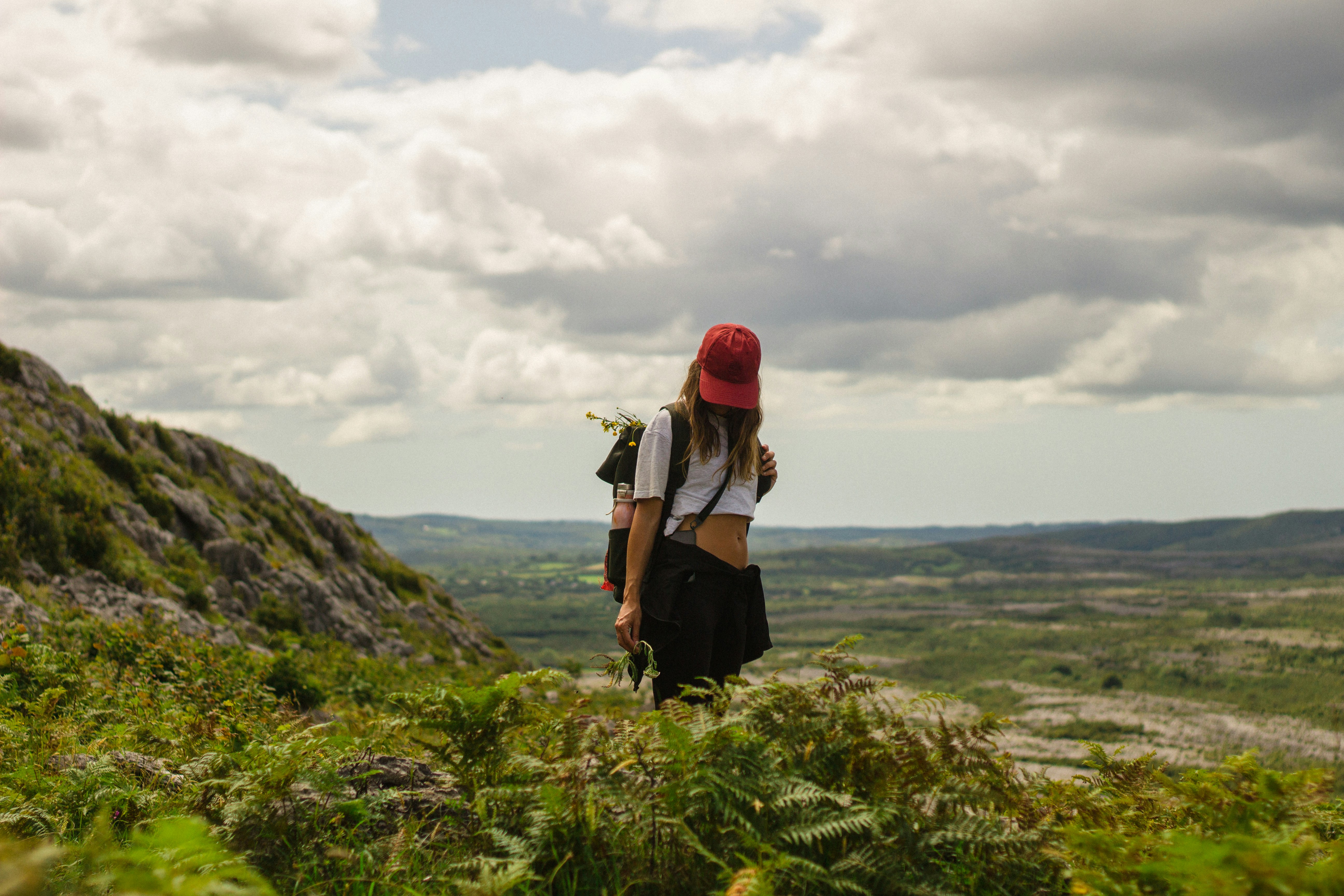 Randonneur avec sac à dos sur une colline herbeuse surplombant le paysage