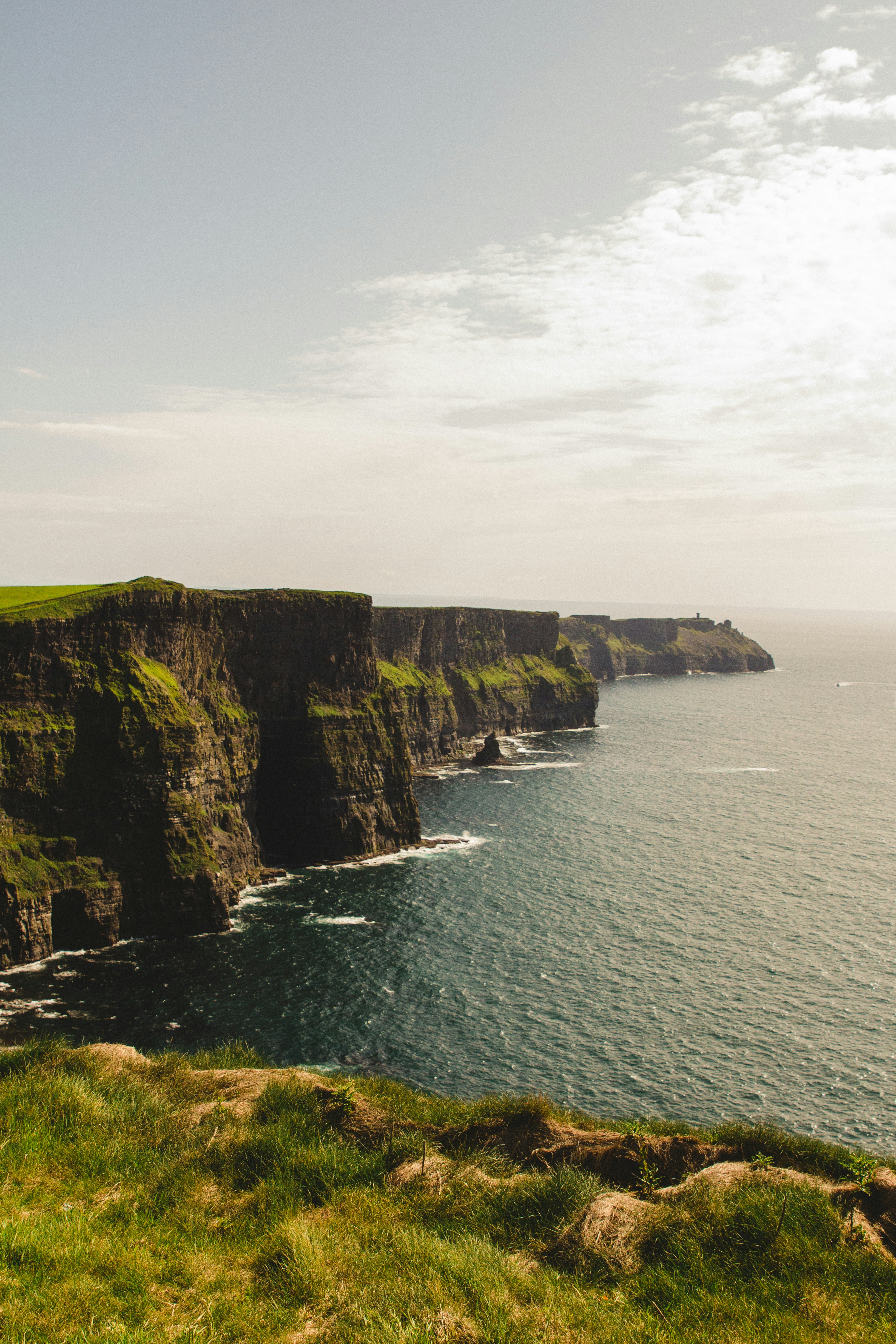Des falaises spectaculaires rencontrent l’océan sous un ciel nuageux