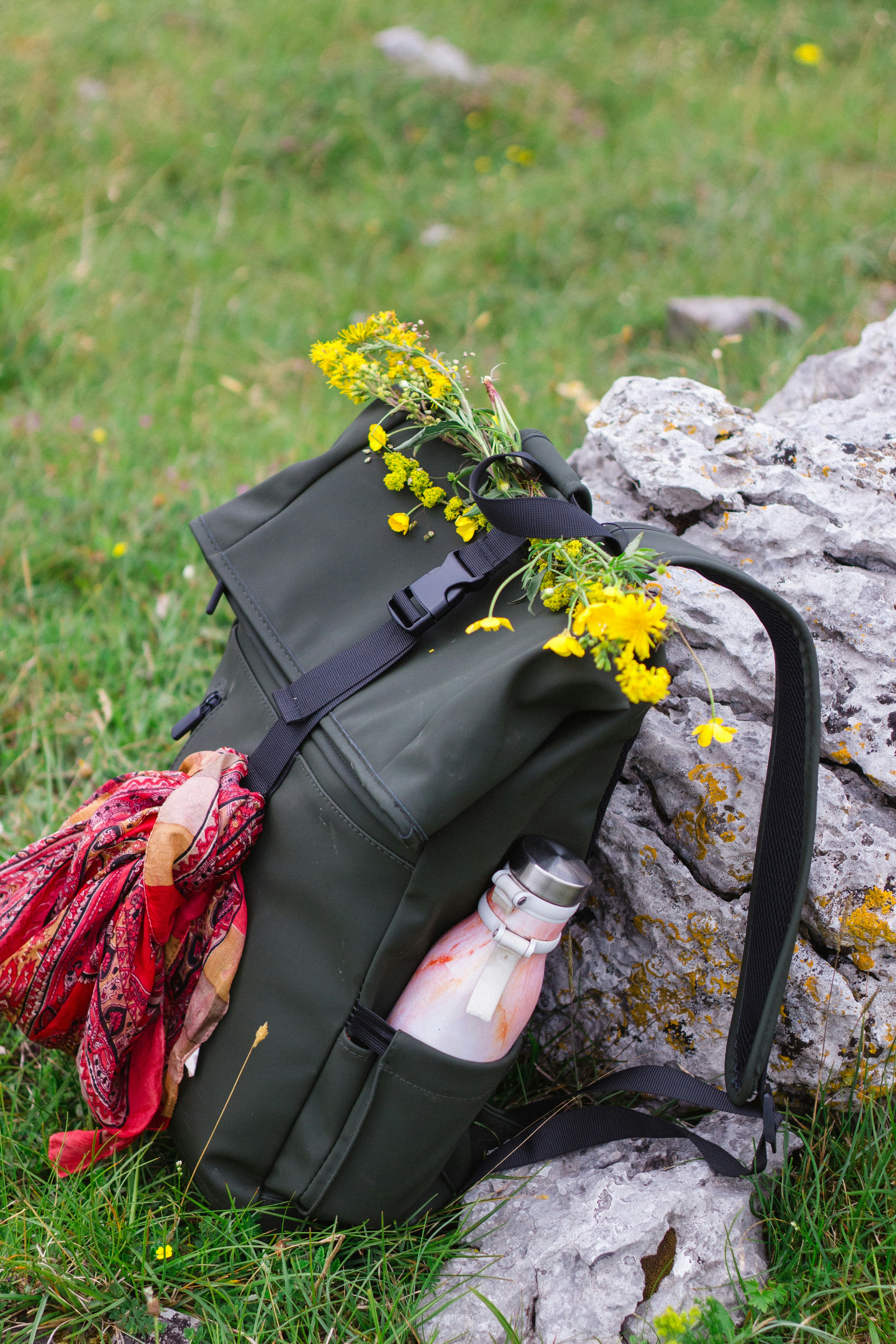 Sac à dos vert avec fleurs et écharpe sur rochers