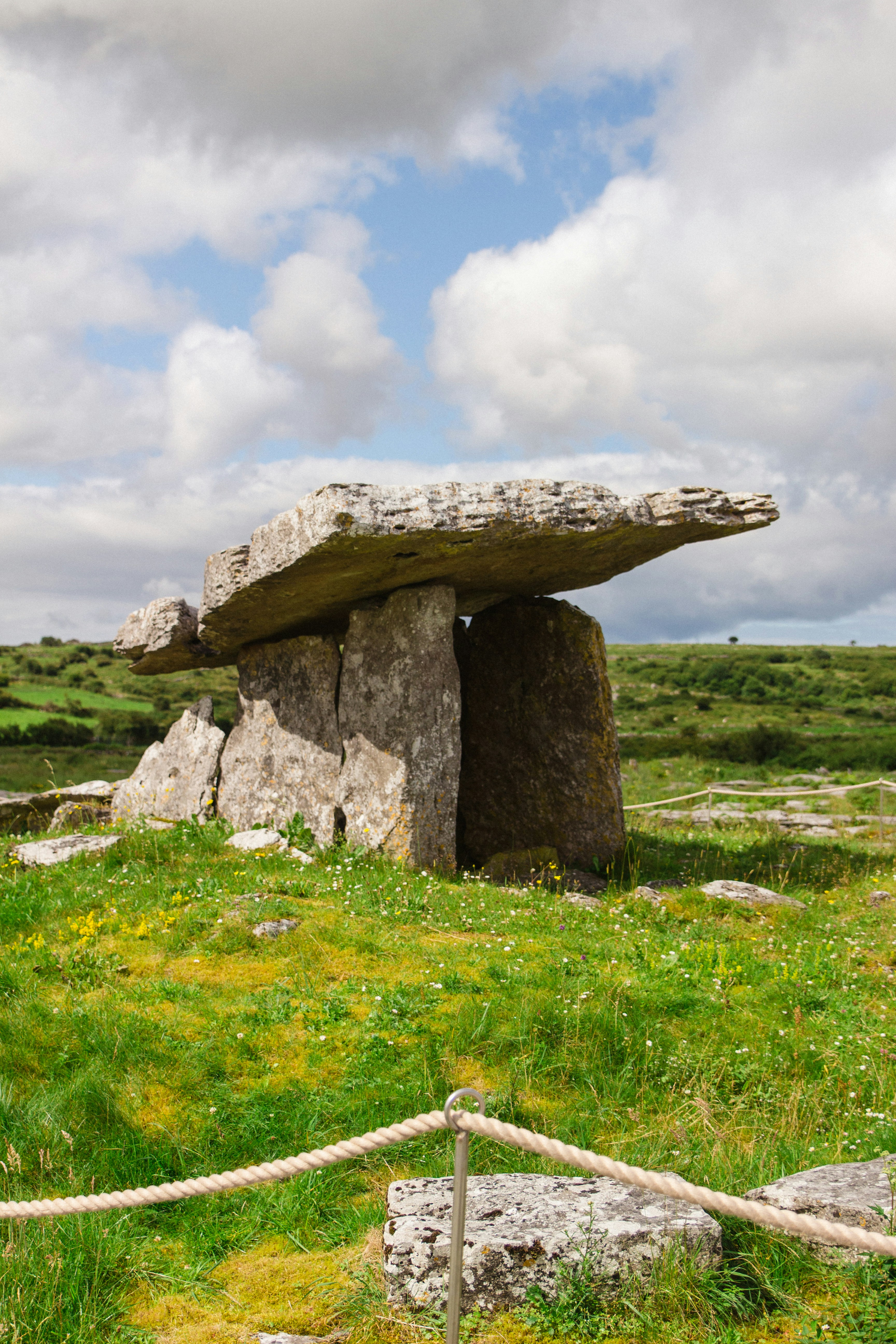 Ancienne tombe en pierre dans un champ herbeux sous les nuages