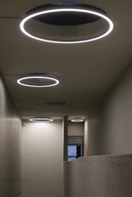 Modern circular ceiling lights illuminate a hallway.