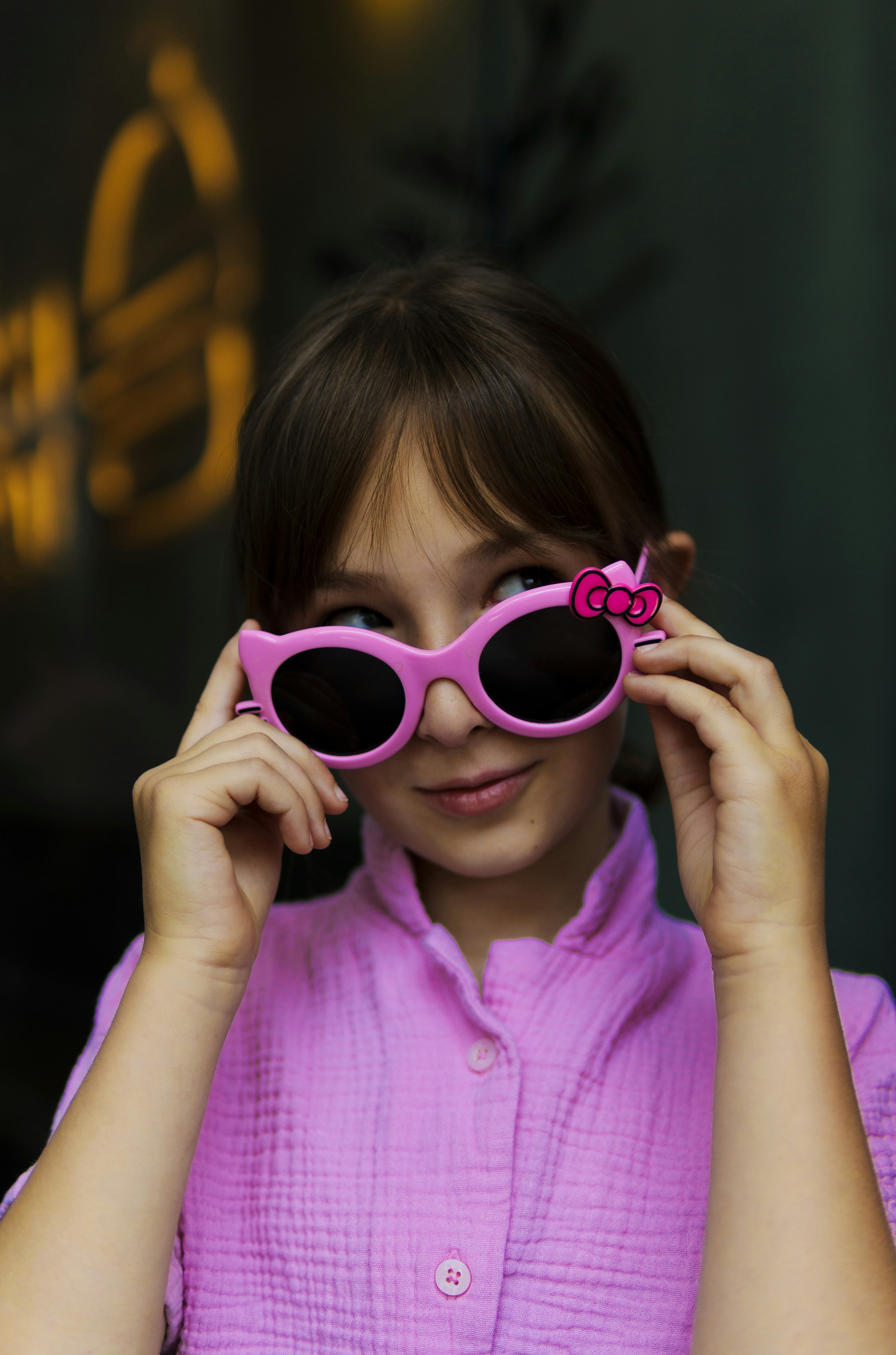 Giovane ragazza che indossa occhiali da sole rosa e camicia rosa