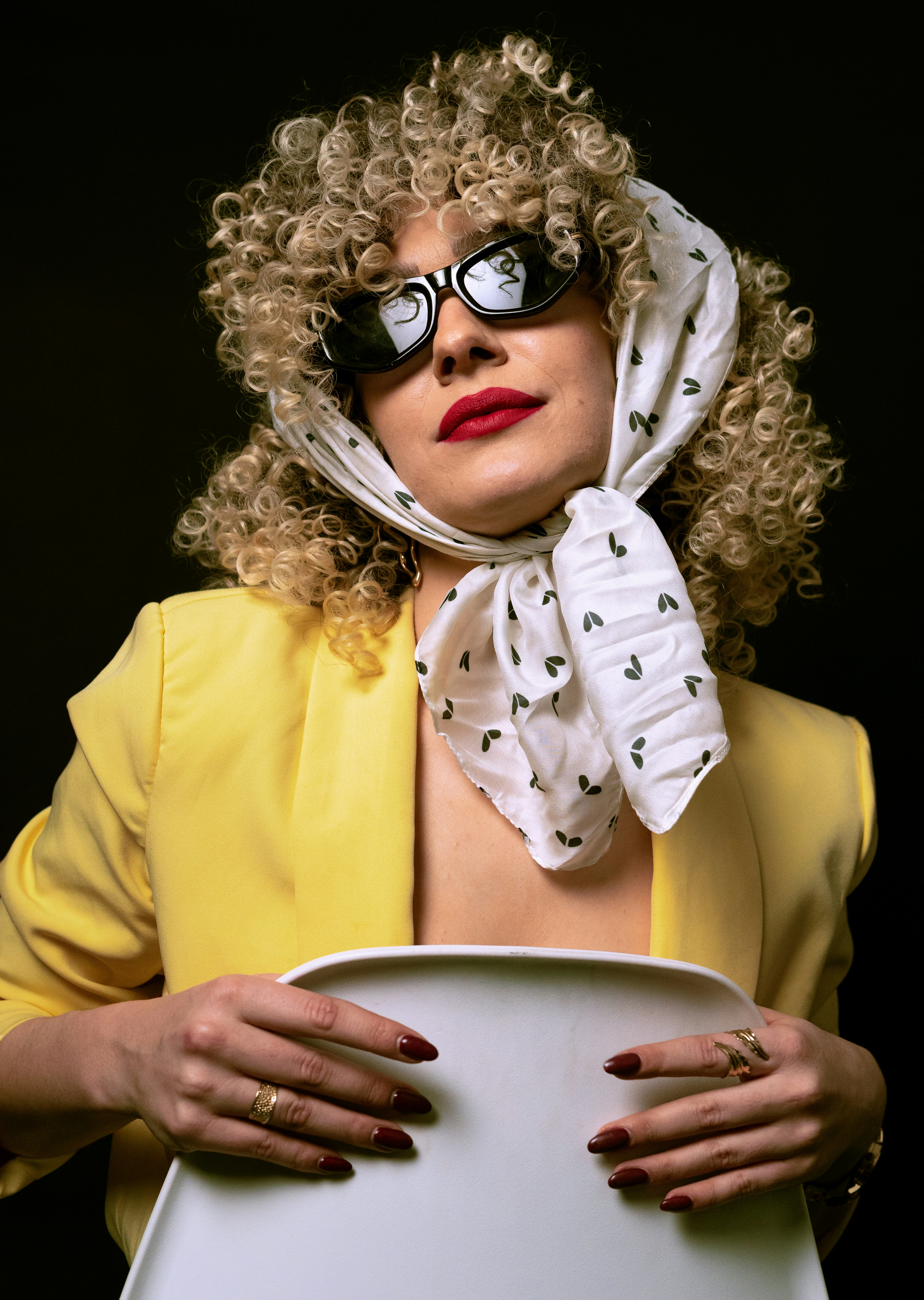 La donna con i capelli ricci e la sciarpa posa con sicurezza