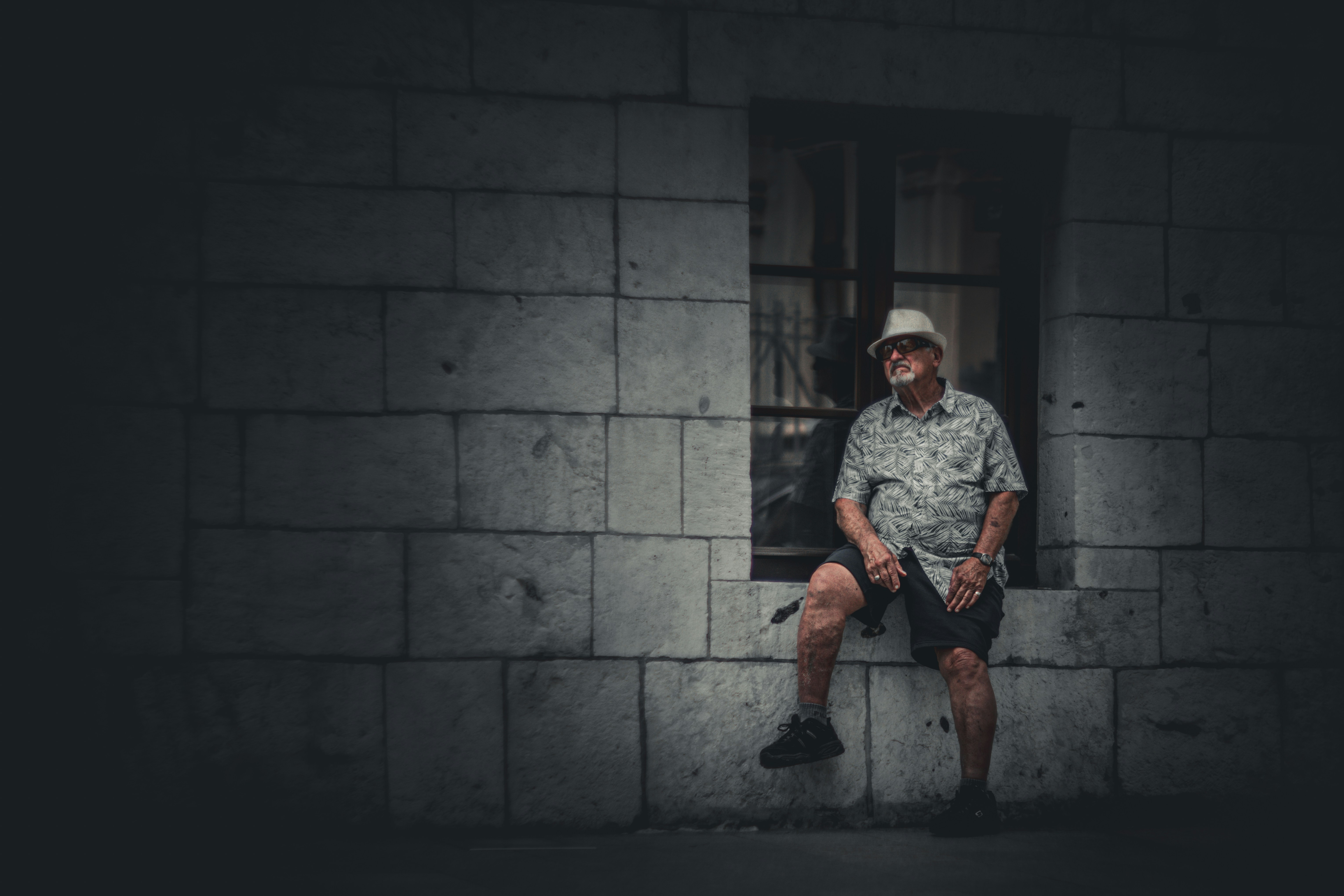 Man wearing sunglasses and hat sits in doorway