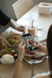 People taking photos of food at a cafe table.