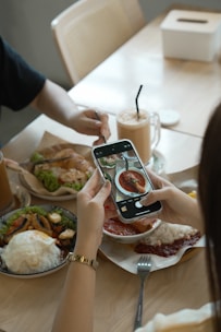 People taking photos of food at a cafe table.