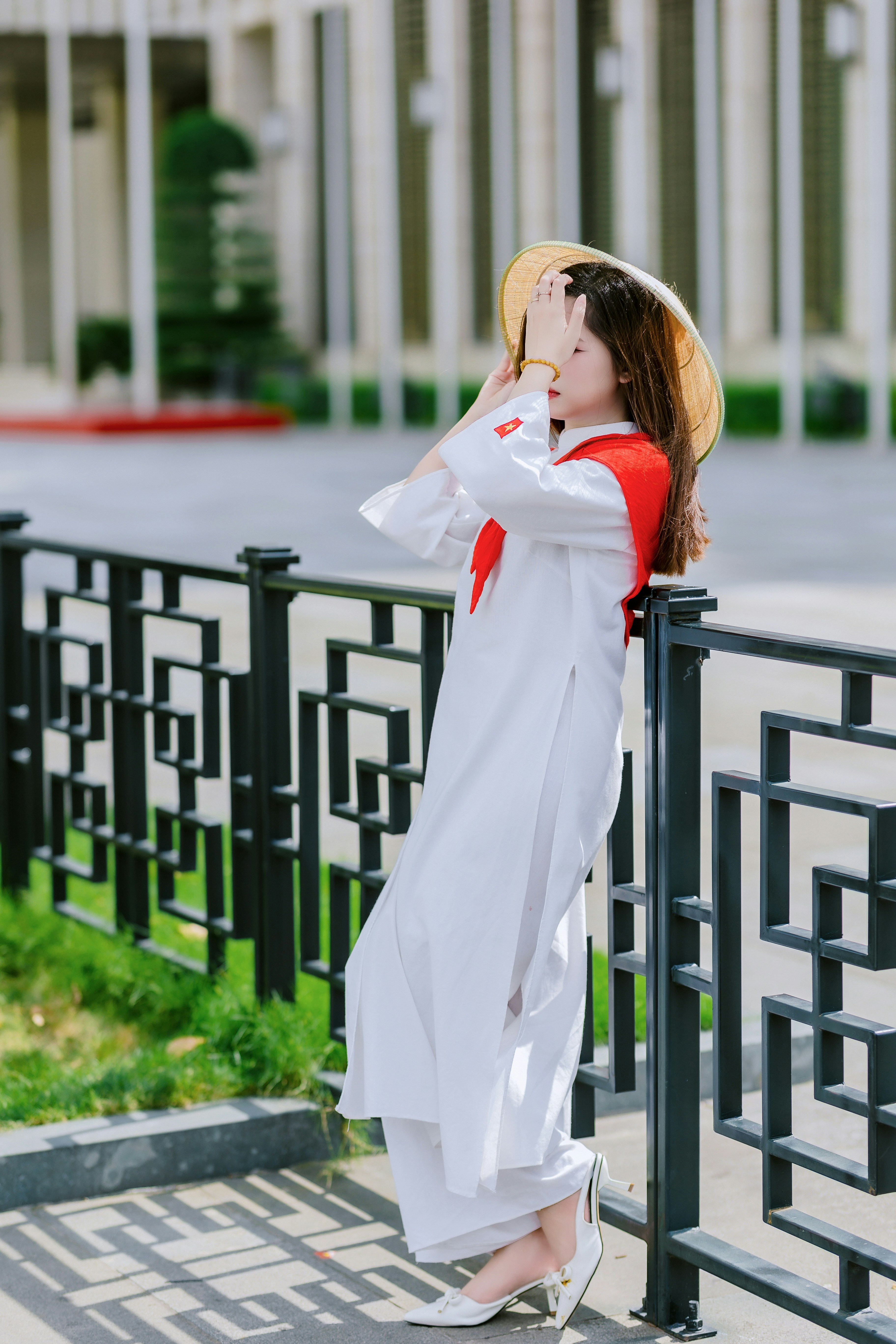 Wanita dengan ao dai tradisional vietnam dan topi berbentuk kerucut.