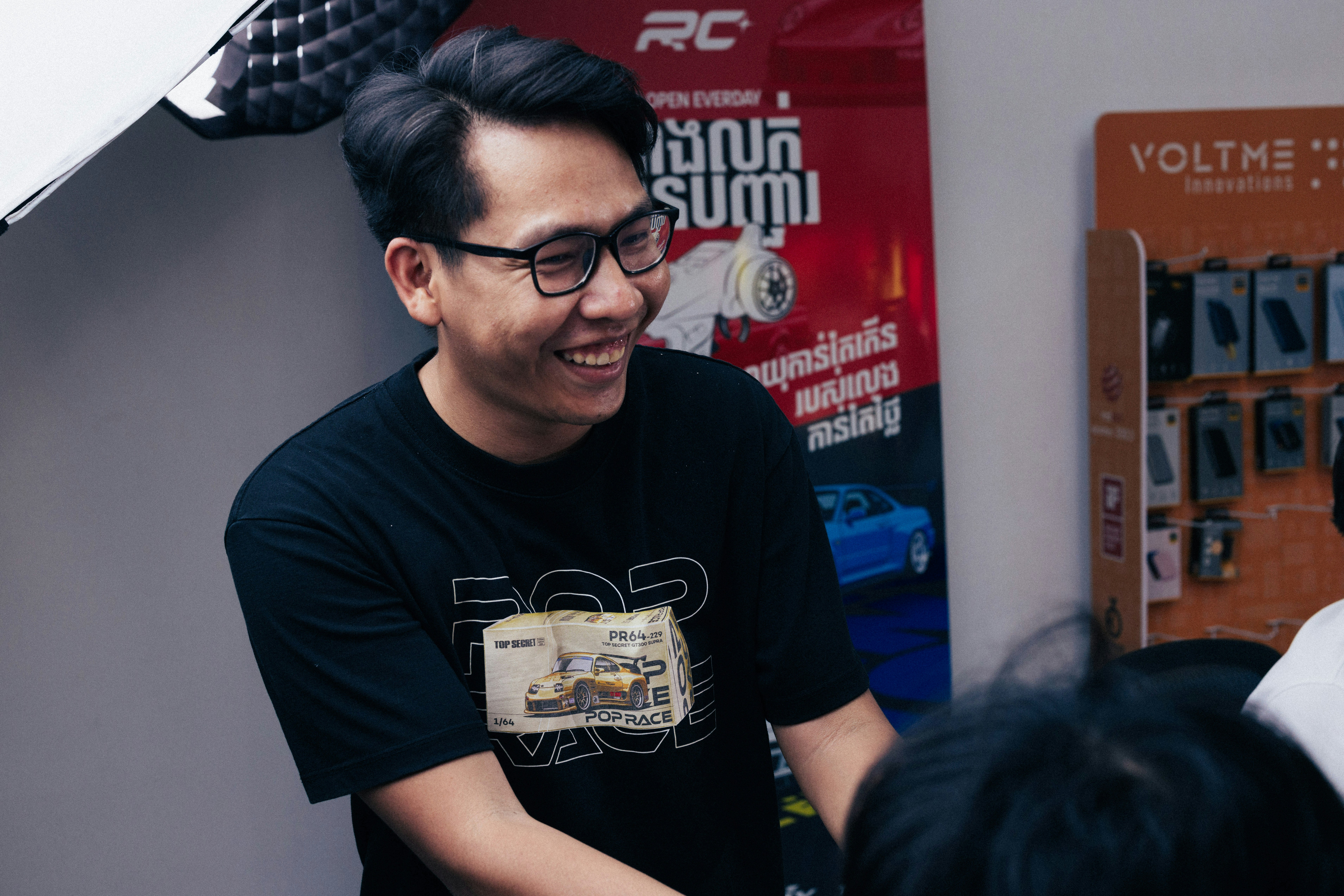 Pria mengenakan kacamata dan kaos hitam tersenyum.