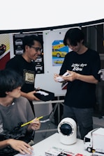Three people looking at something on a table.