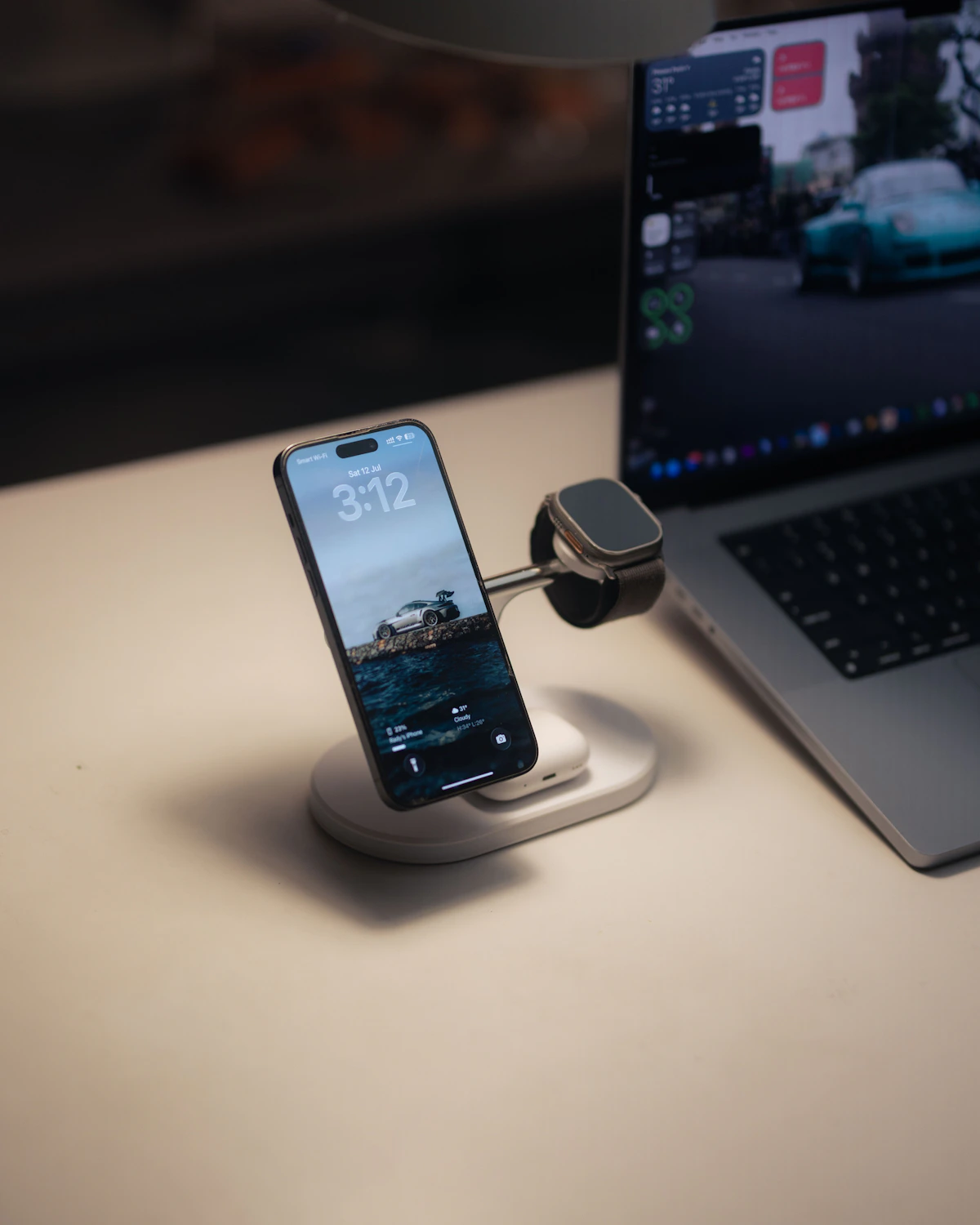 Smartphone and smartwatch charging beside a laptop on a desk