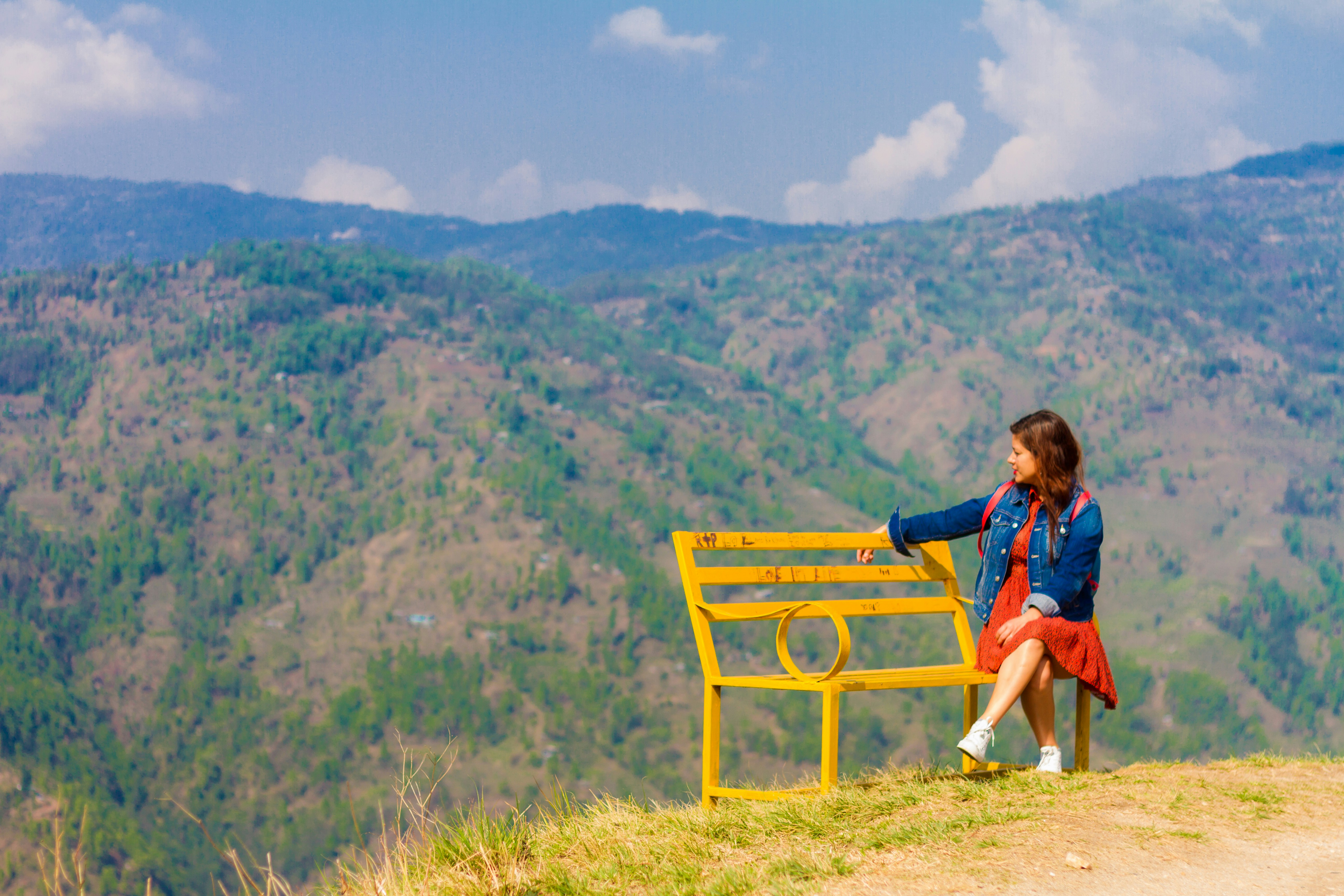 Woman sitting on a bench overlooking mountains