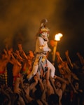 Dancer in elaborate mask carried by performers at night.