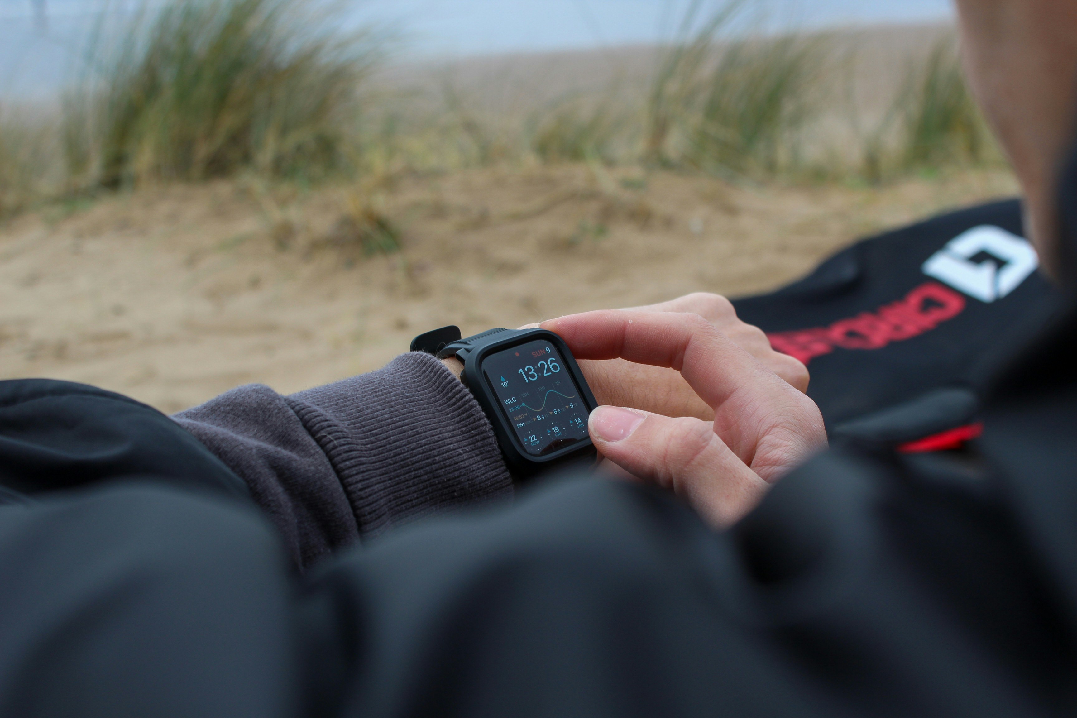 砂浜でスマートウォッチをチェックする人