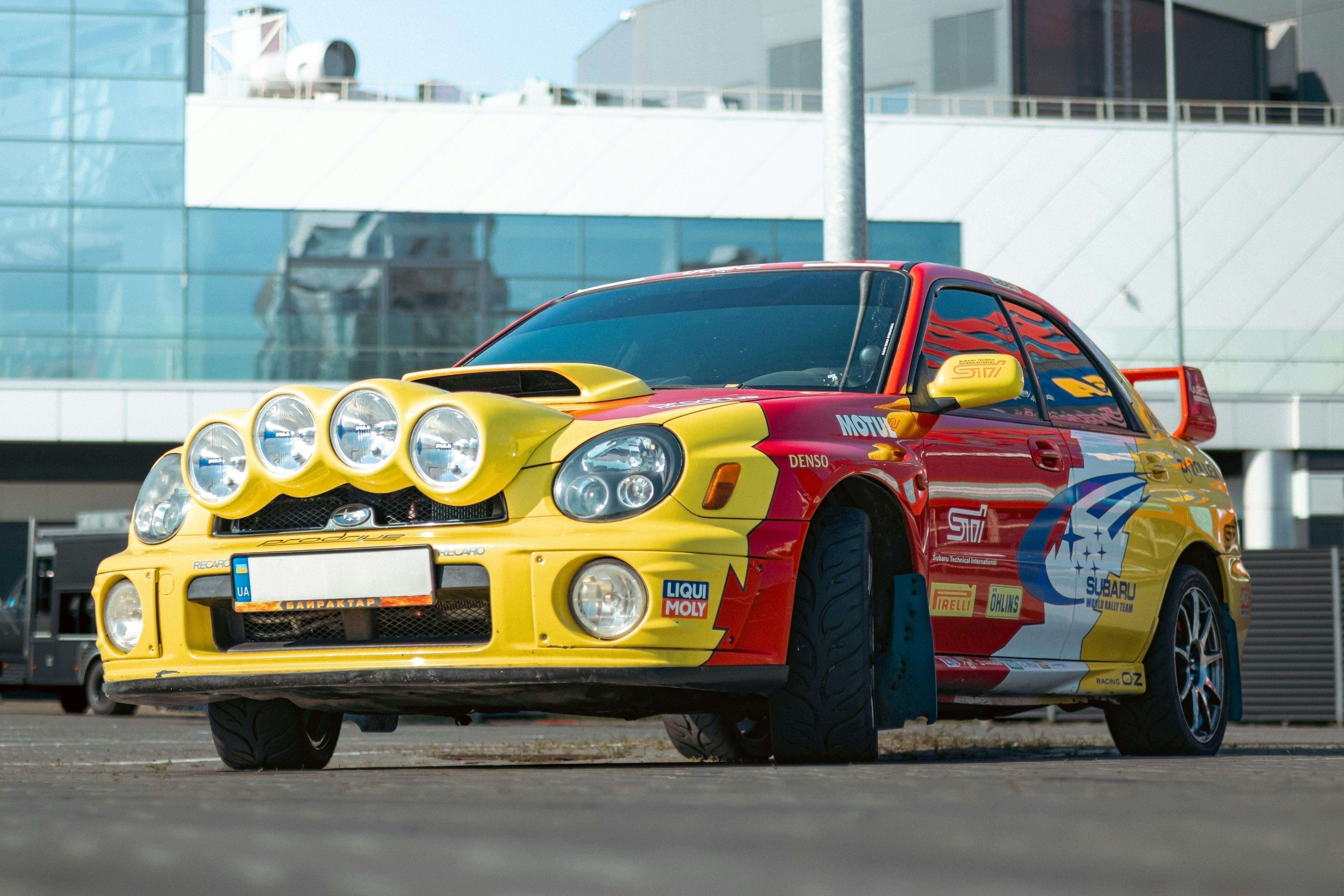 Colorful rally car parked in front of a modern building