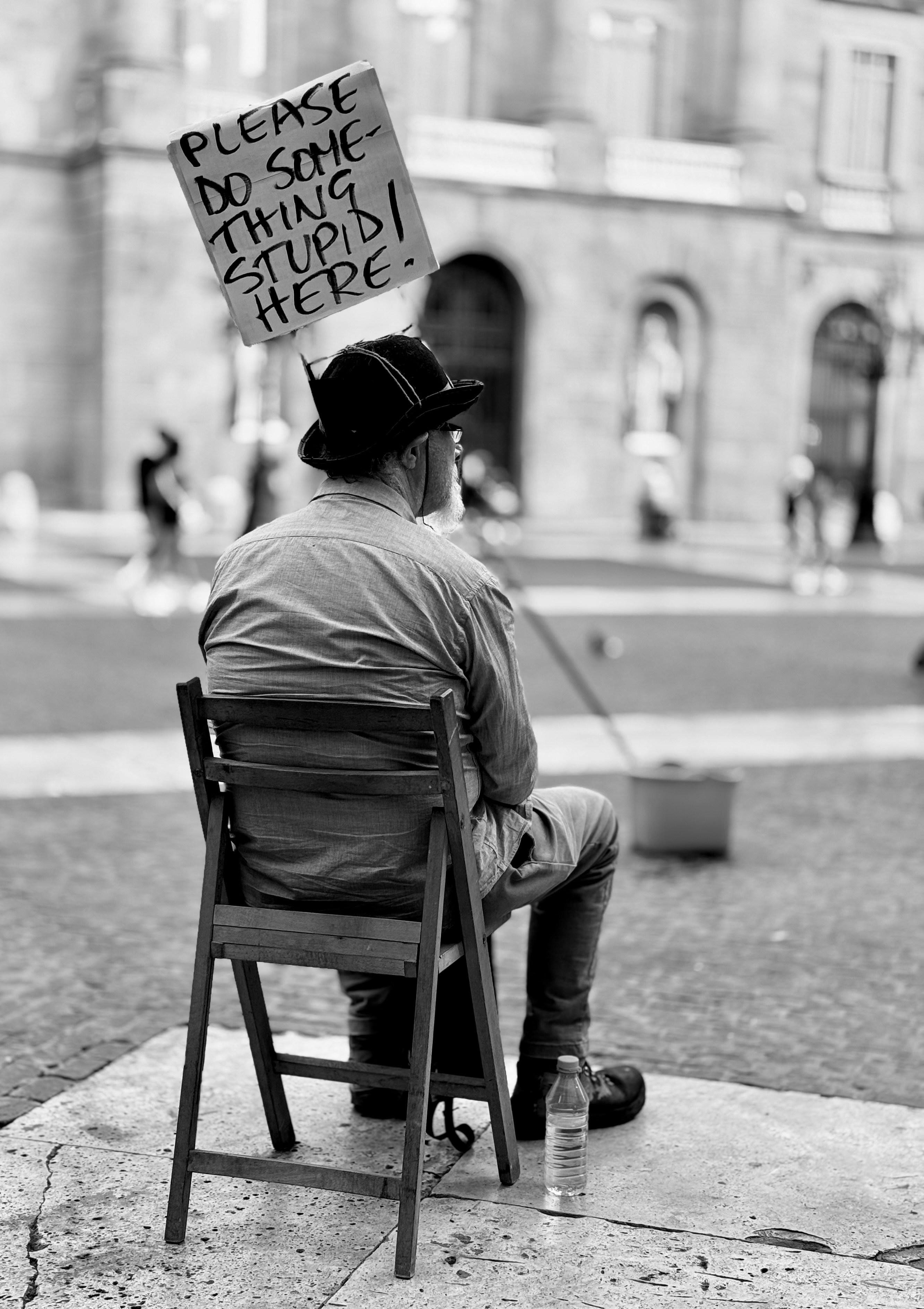 Man sitting outside holding a sign.