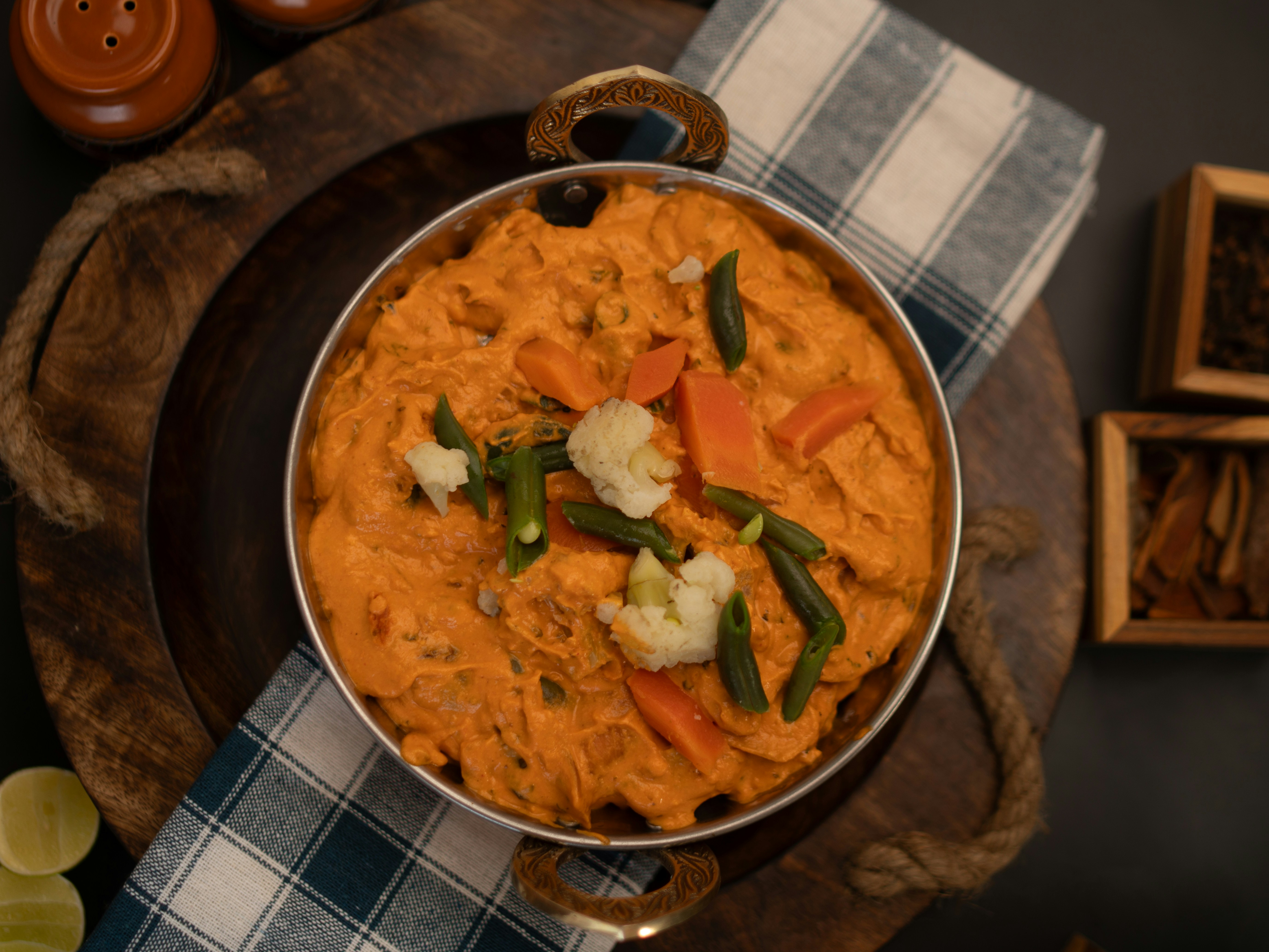 A pot of delicious orange curry with garnishes.