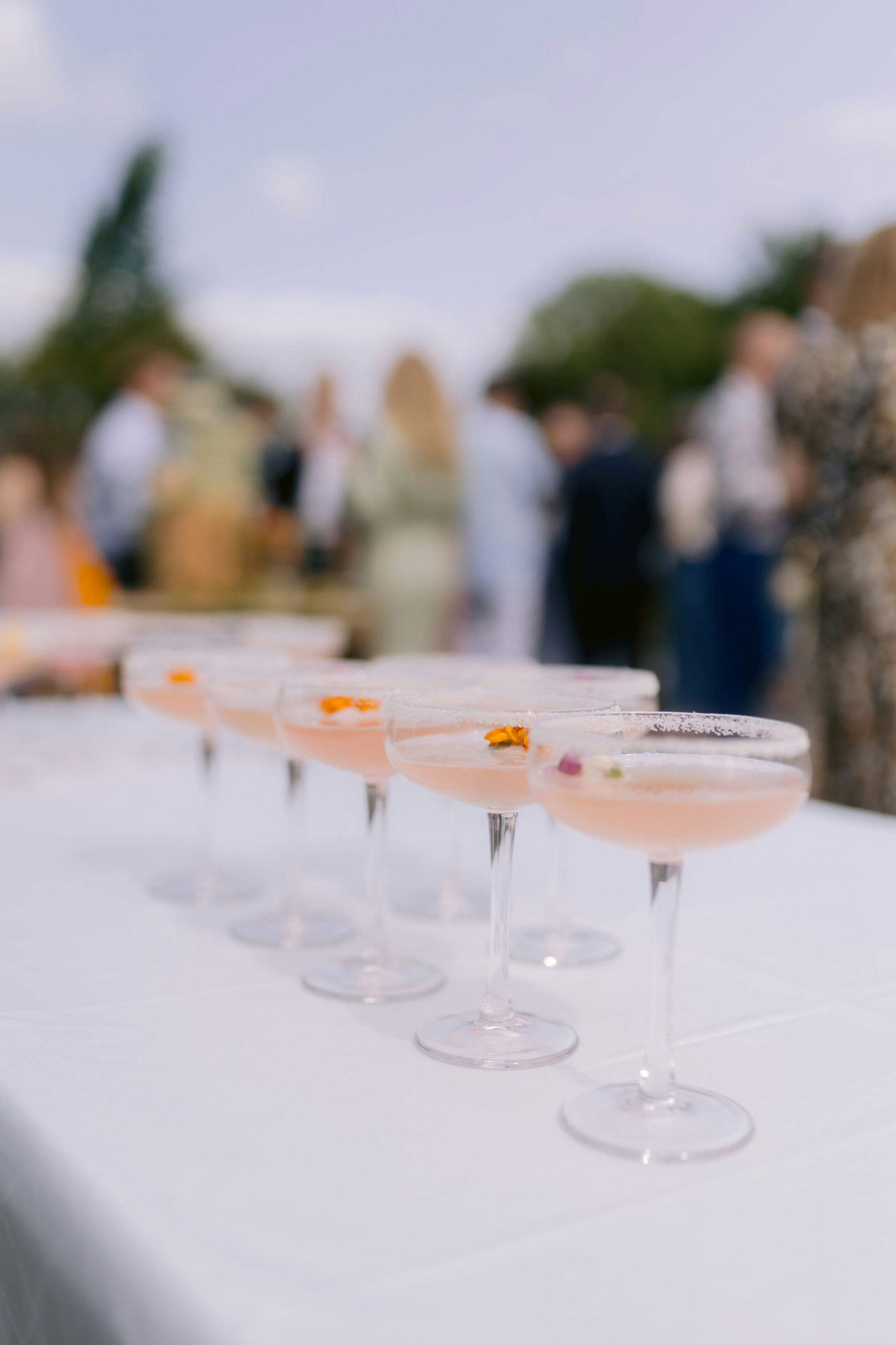 Row of champagne glasses with pink drinks.