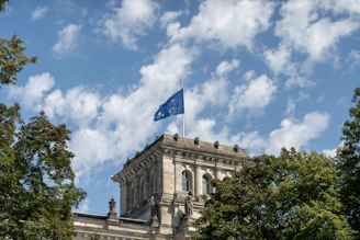 European union flag flies over building with trees