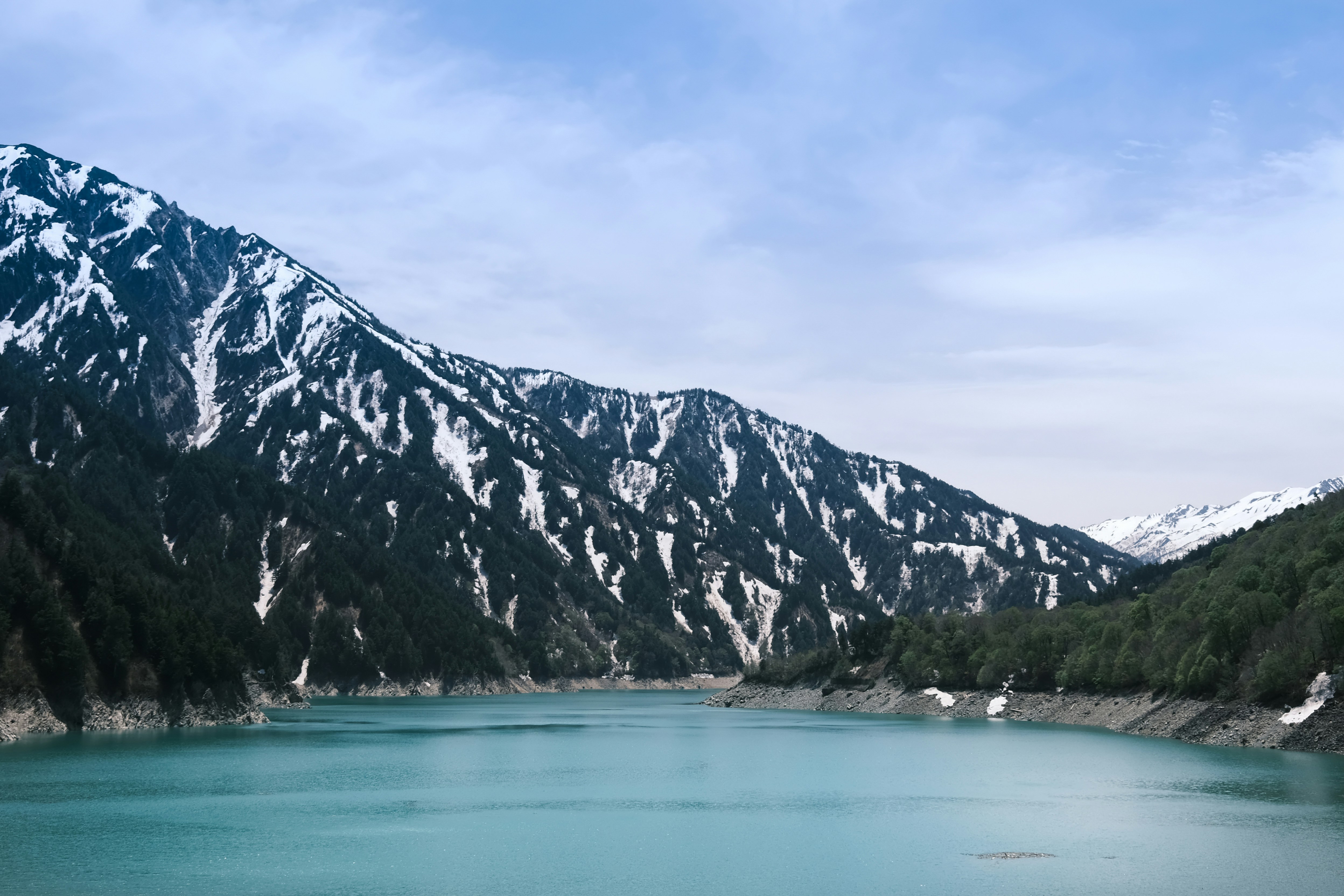 Turquoise lake with snow-capped mountains and forest