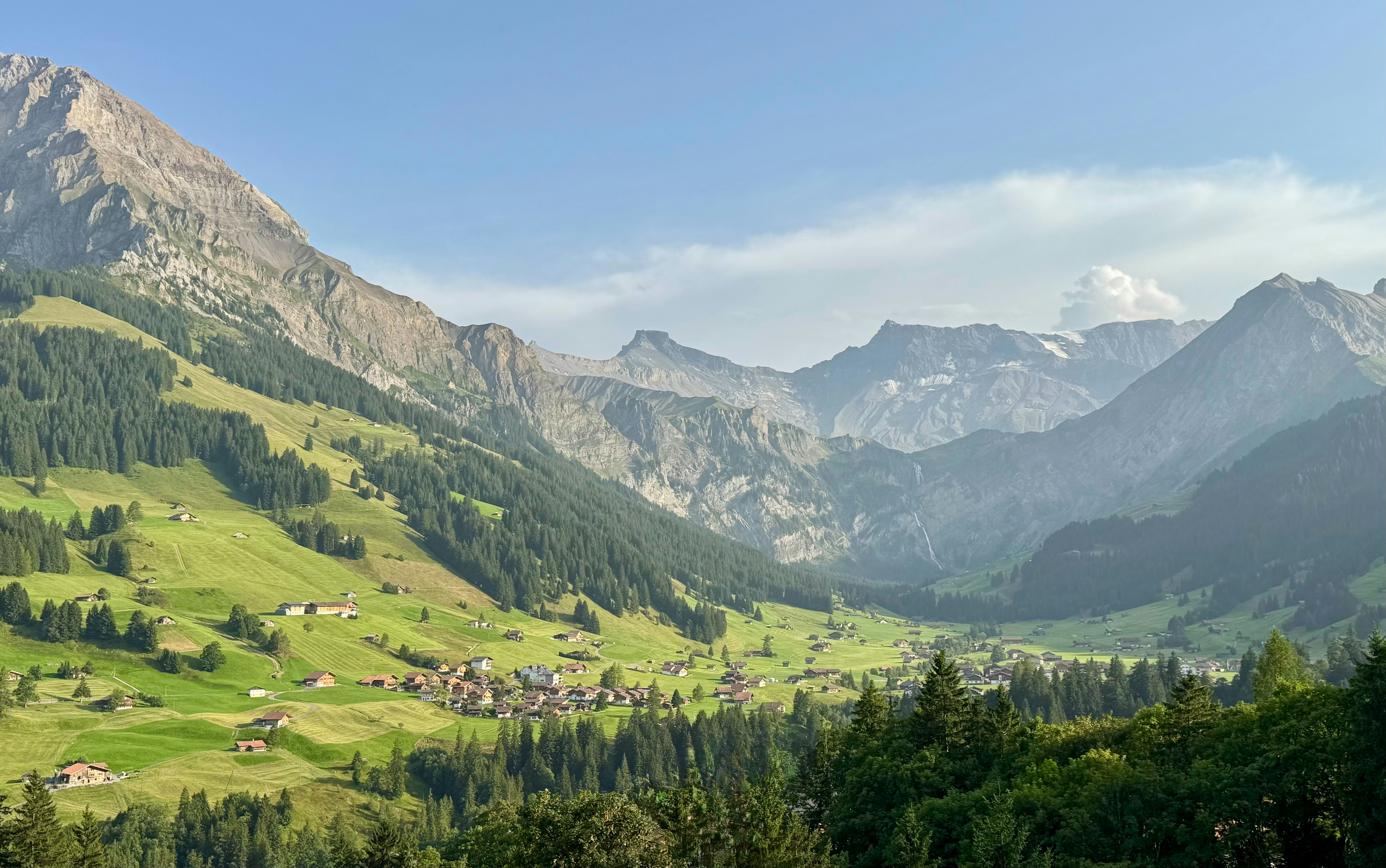 Lush green valley surrounded by majestic mountains under a clear sky.