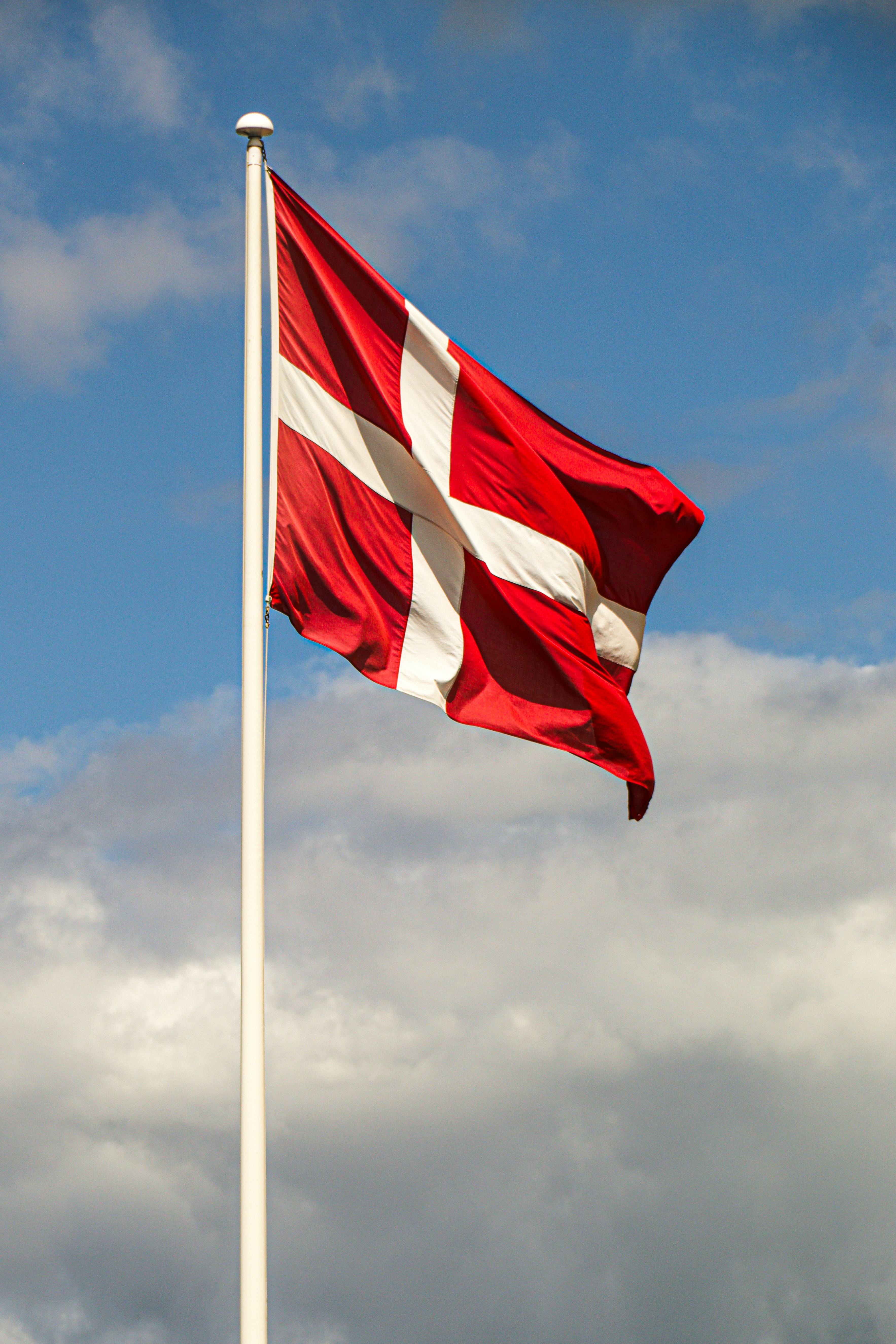 Danish flag waving against a cloudy blue sky