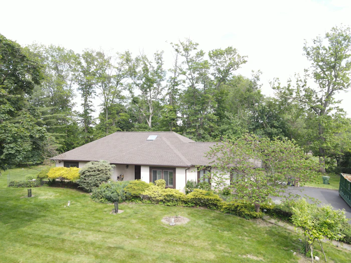 A low bungalow with a grey hip roof on a sloping lawn