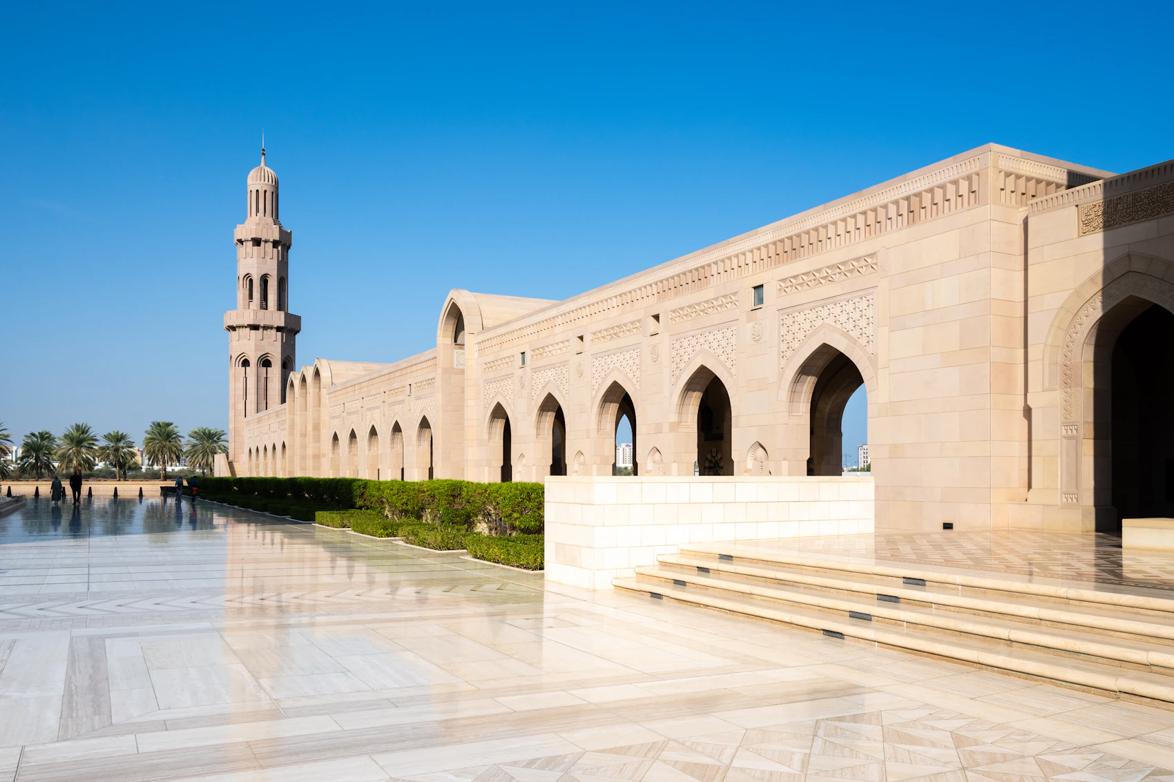 The pale stone arches and minaret of Sultan Qaboos Grand Mosque in Muscat