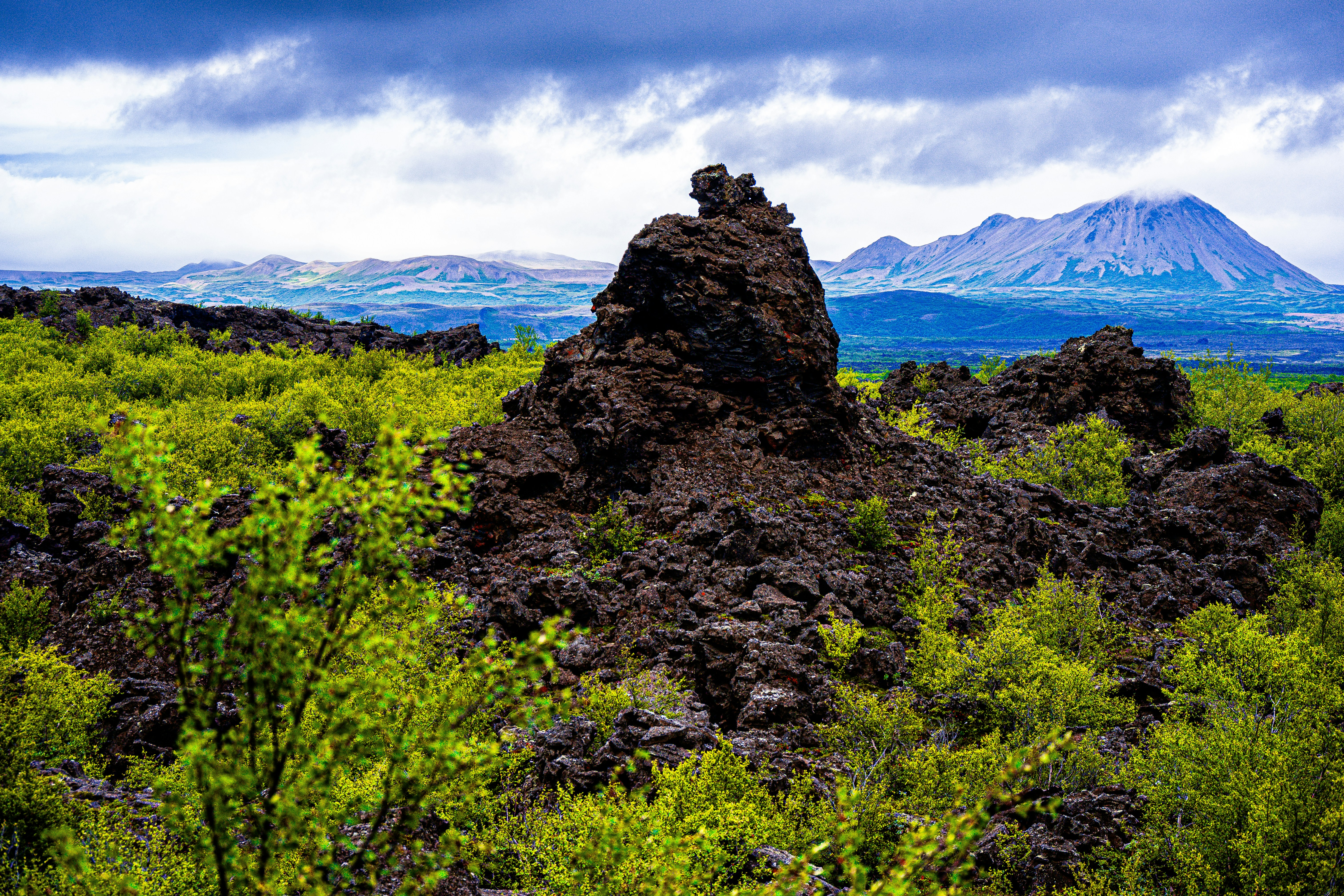 Rocky outcrop in a green landscape with mountains